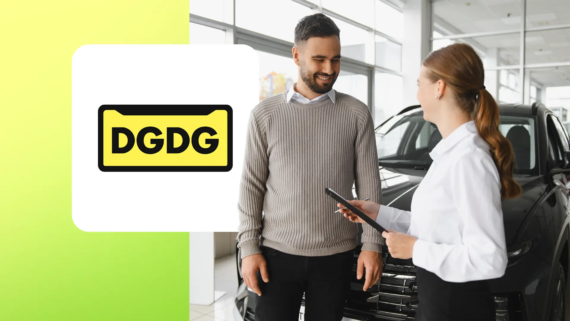 Man in gray sweater and woman with clipboard stand in front of a black car inside a showroom.