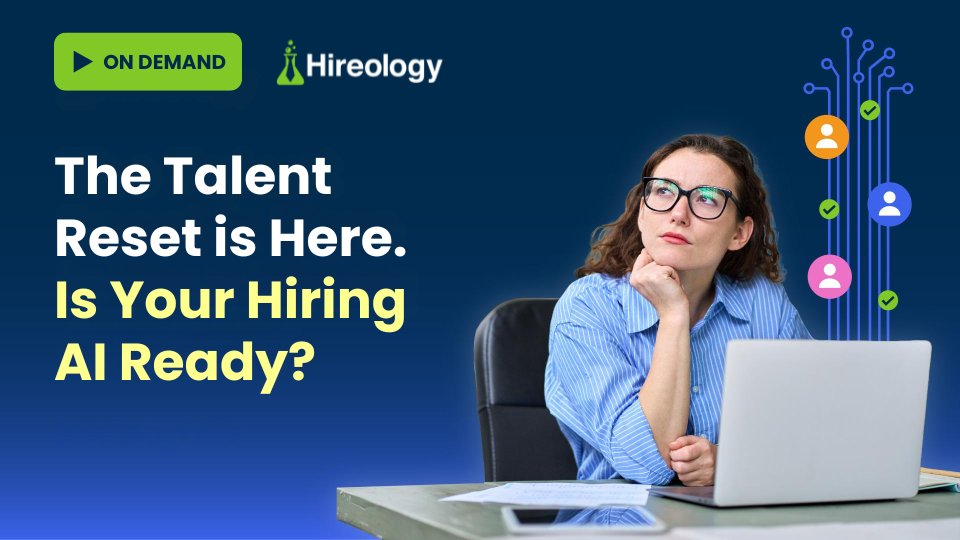 Woman in glasses sitting at desk with laptop, thinking about AI-driven hiring and talent reset.