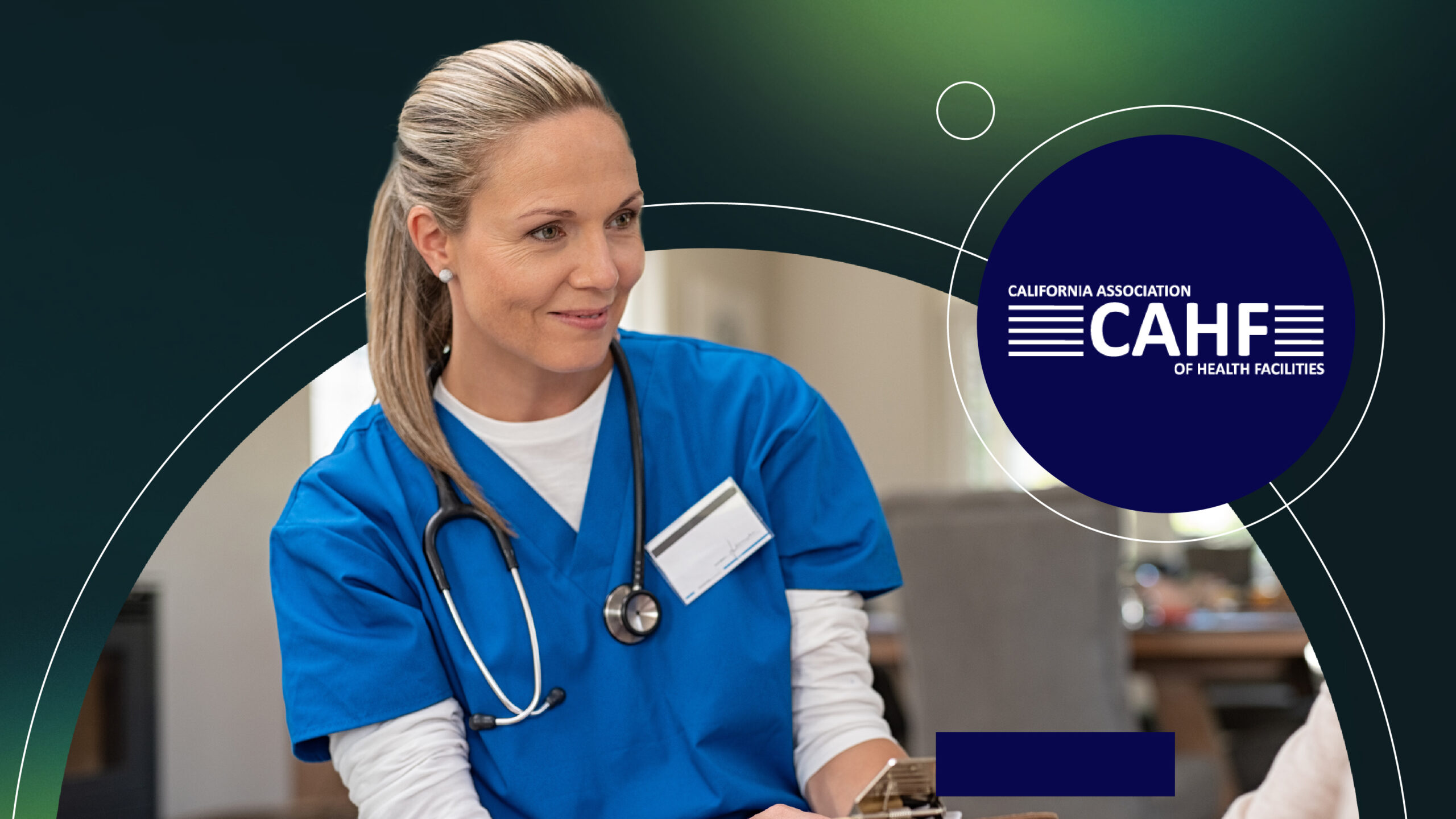 Female healthcare worker in blue scrubs with stethoscope, smiling and holding a clipboard.
