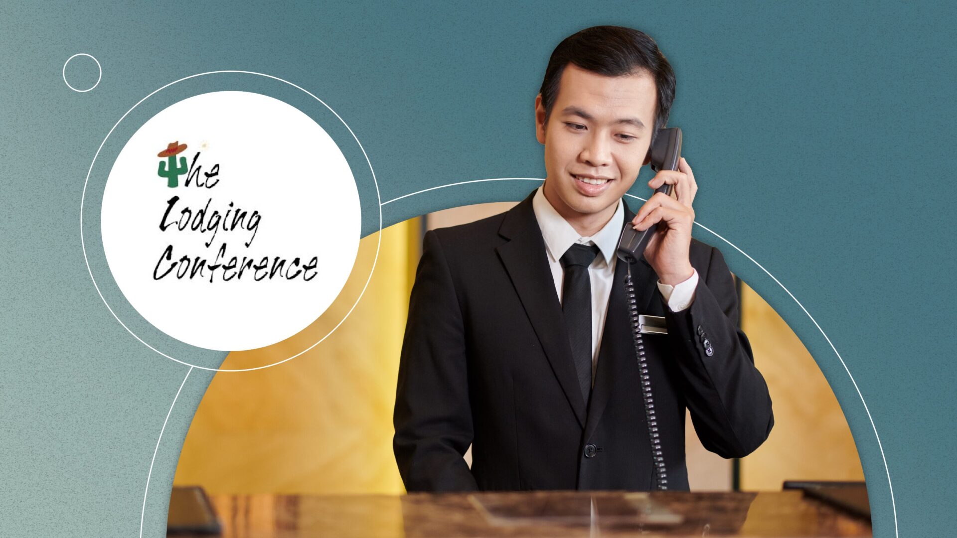 Hotel receptionist in a black suit talking on a phone behind a front desk at a conference.