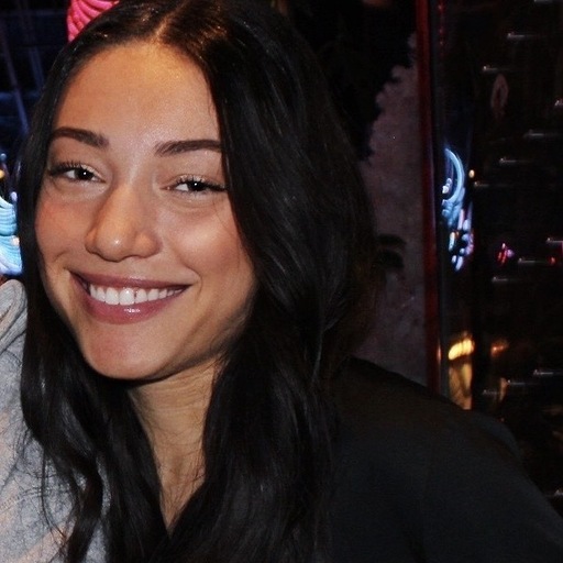Smiling woman with long dark hair wearing a black top.