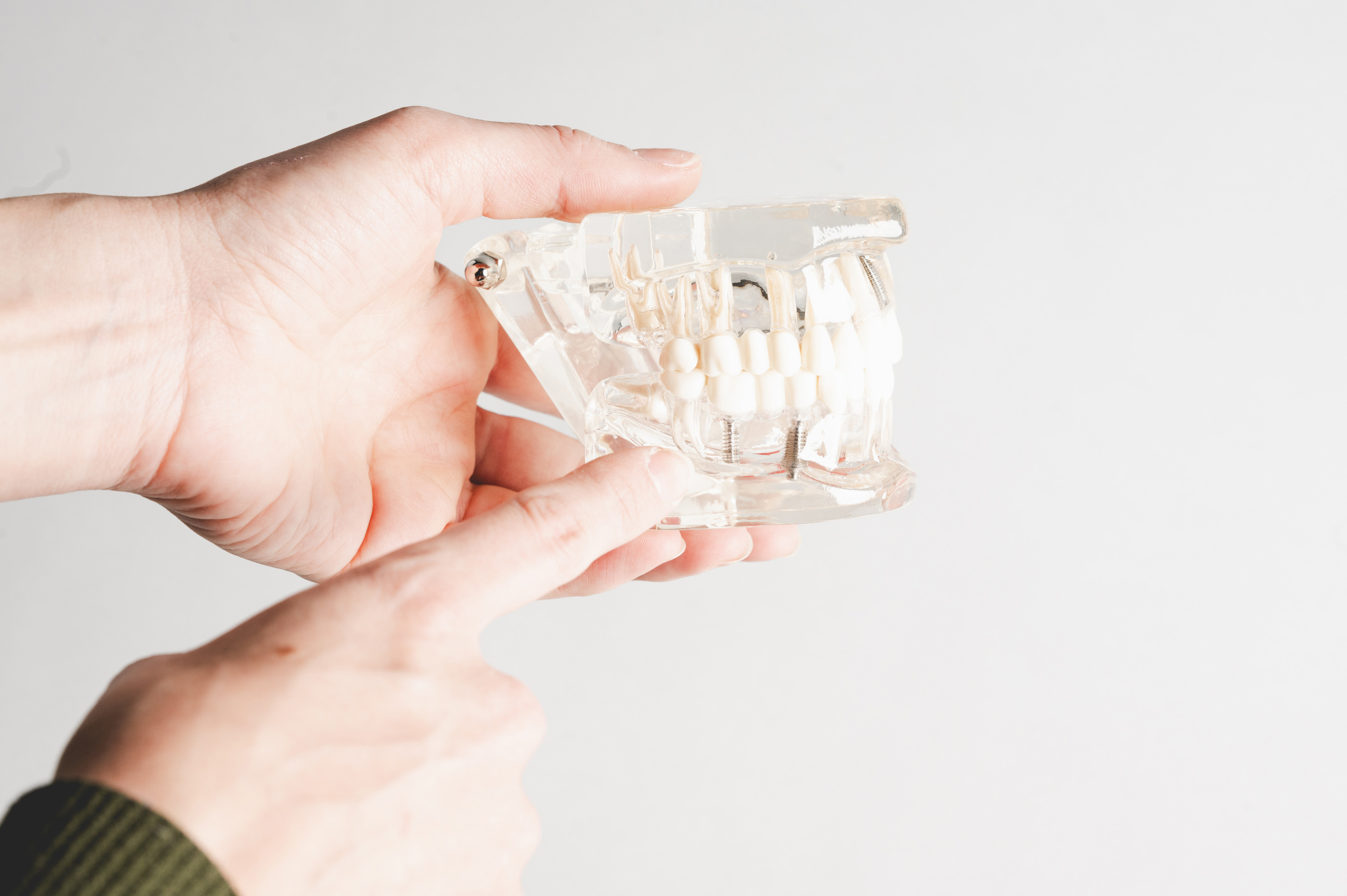 Toothbrush, toothpaste tube, and dental floss container on beige tiled surface.