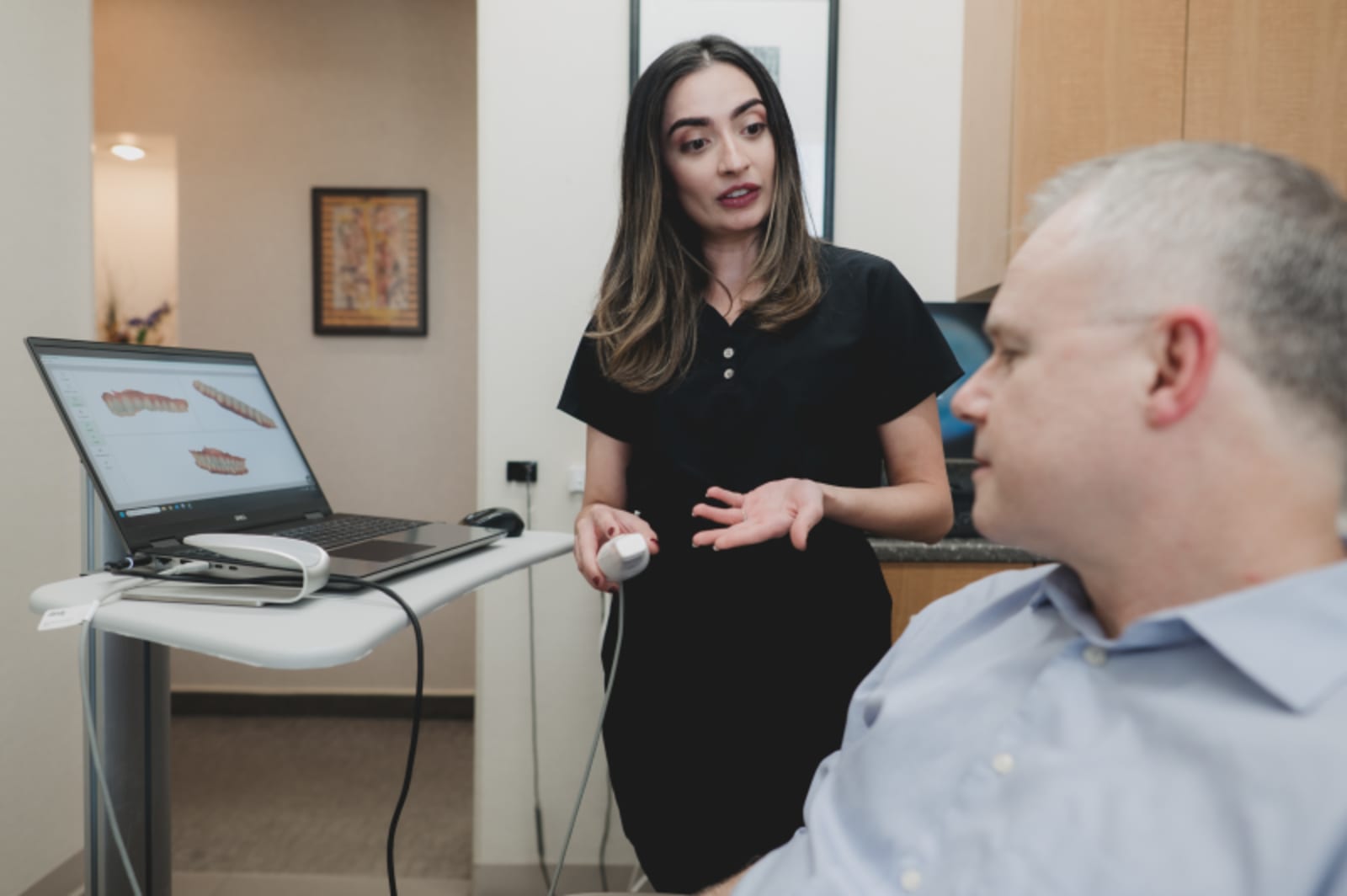 Dentist explaining digital smile design results on laptop to a patient