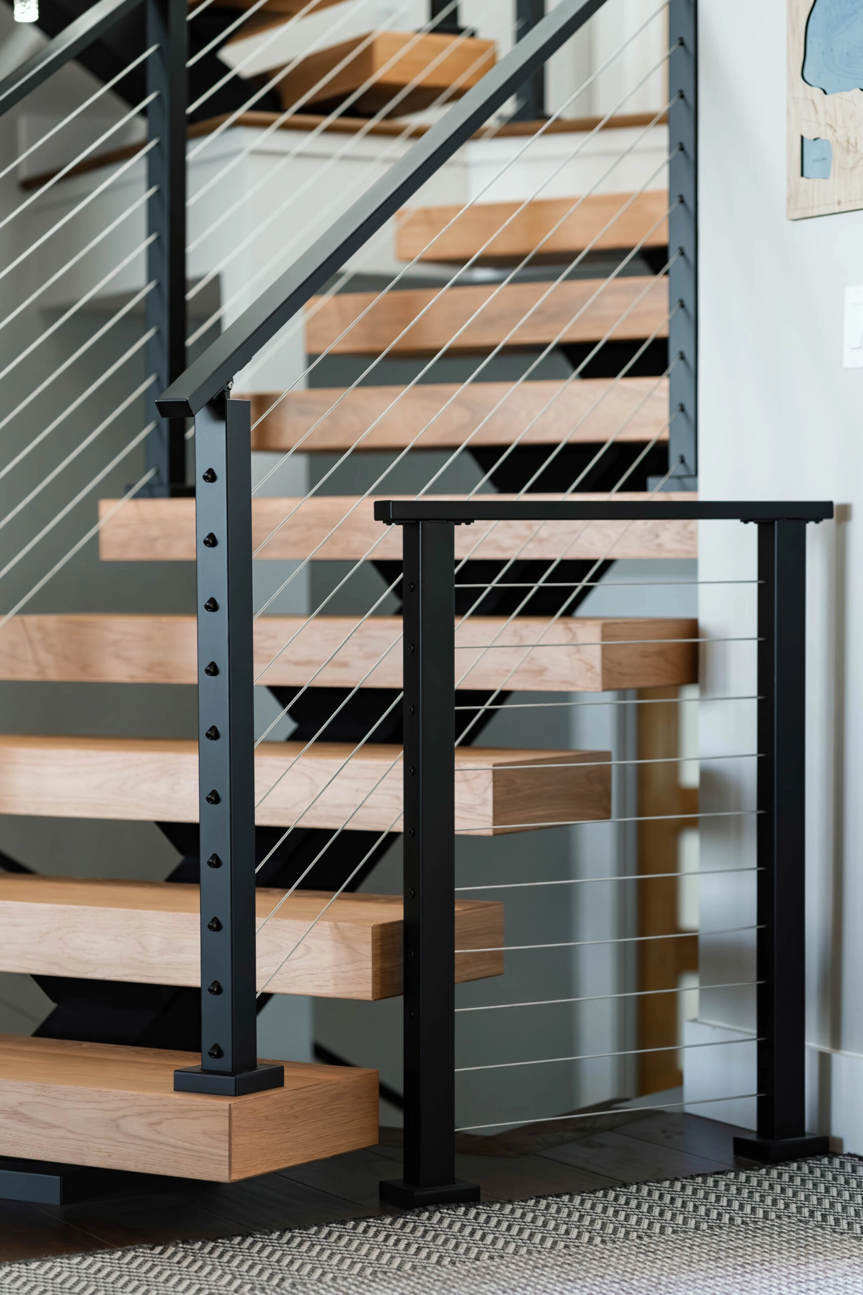 Express cable railing follows a stair run and a level landing in black posts