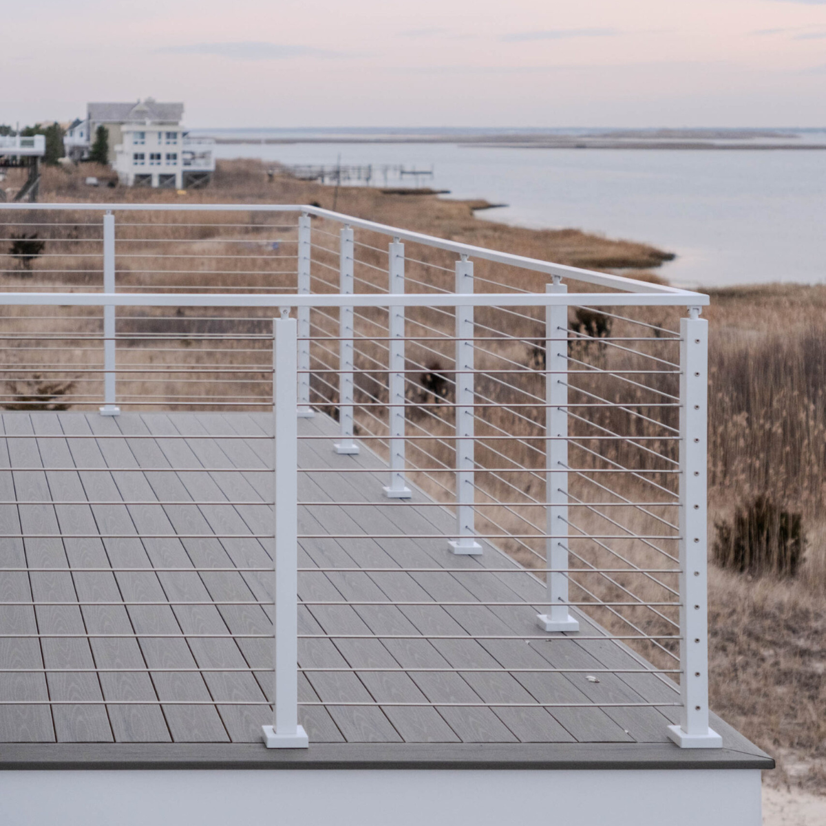 A white railing lines a bayside deck under a soft evening sky