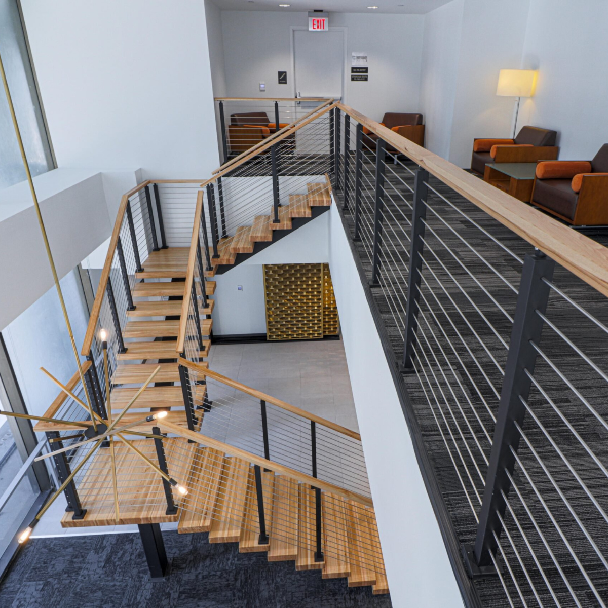 Black posts and a wood handrail follow a balcony edge and the stair below
