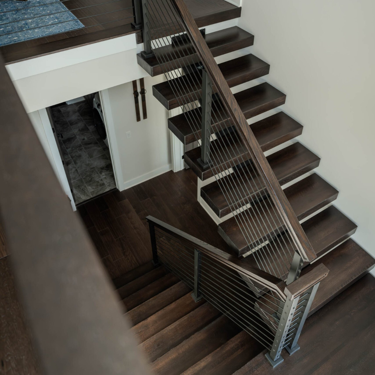Seen from above, rod infill and a wood handrail follow dark stair treads