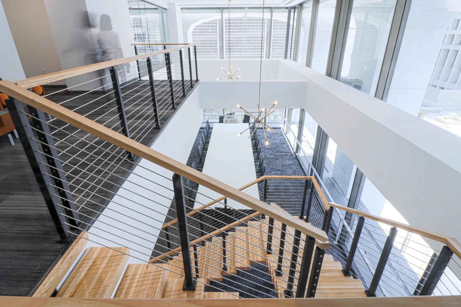 Balcony cable runs framing the atrium opening with the stair descending at left