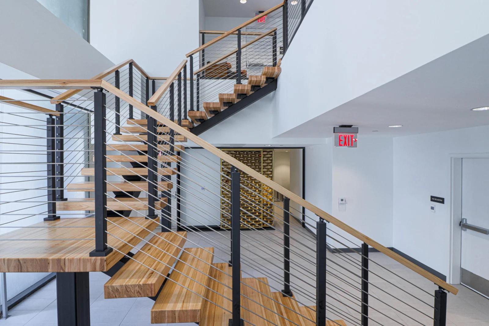 Stair rising behind a thick wood table with wine storage wall beyond