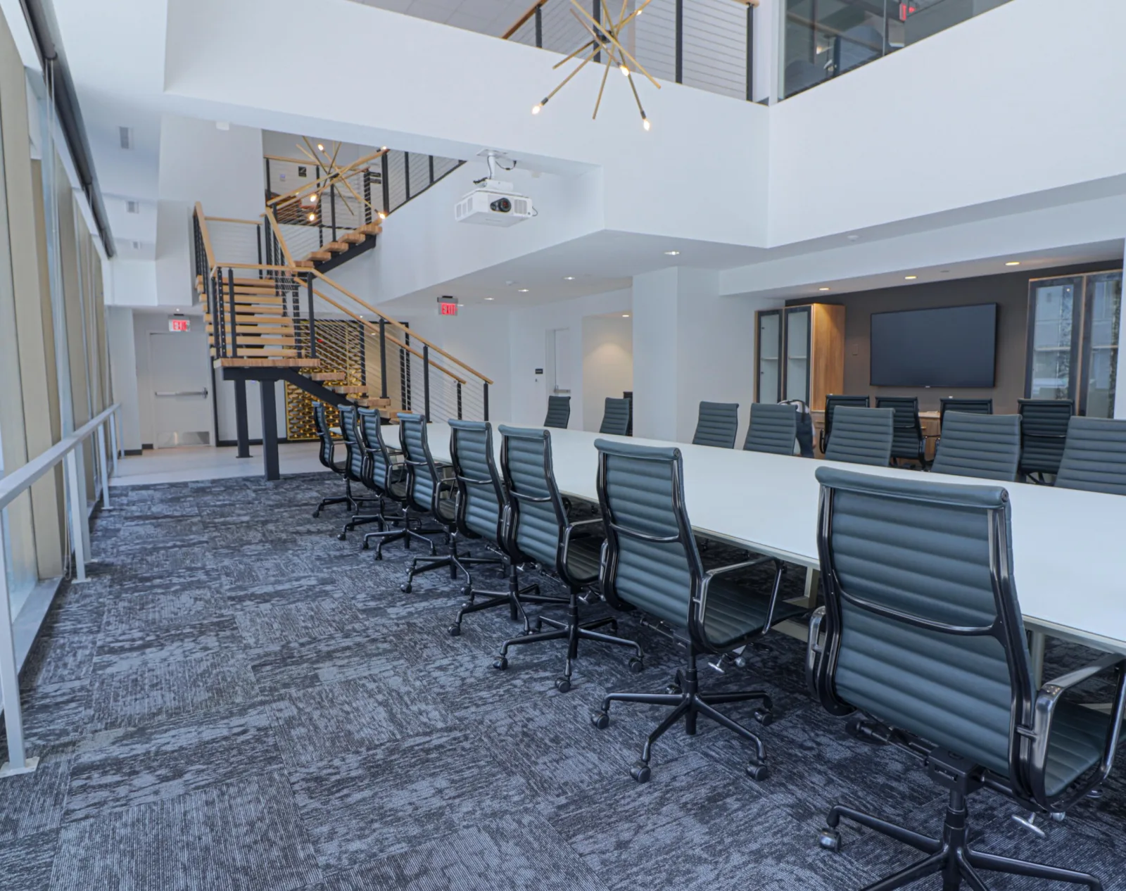 Tall meeting-room view with pendant light fixture and the stair at left