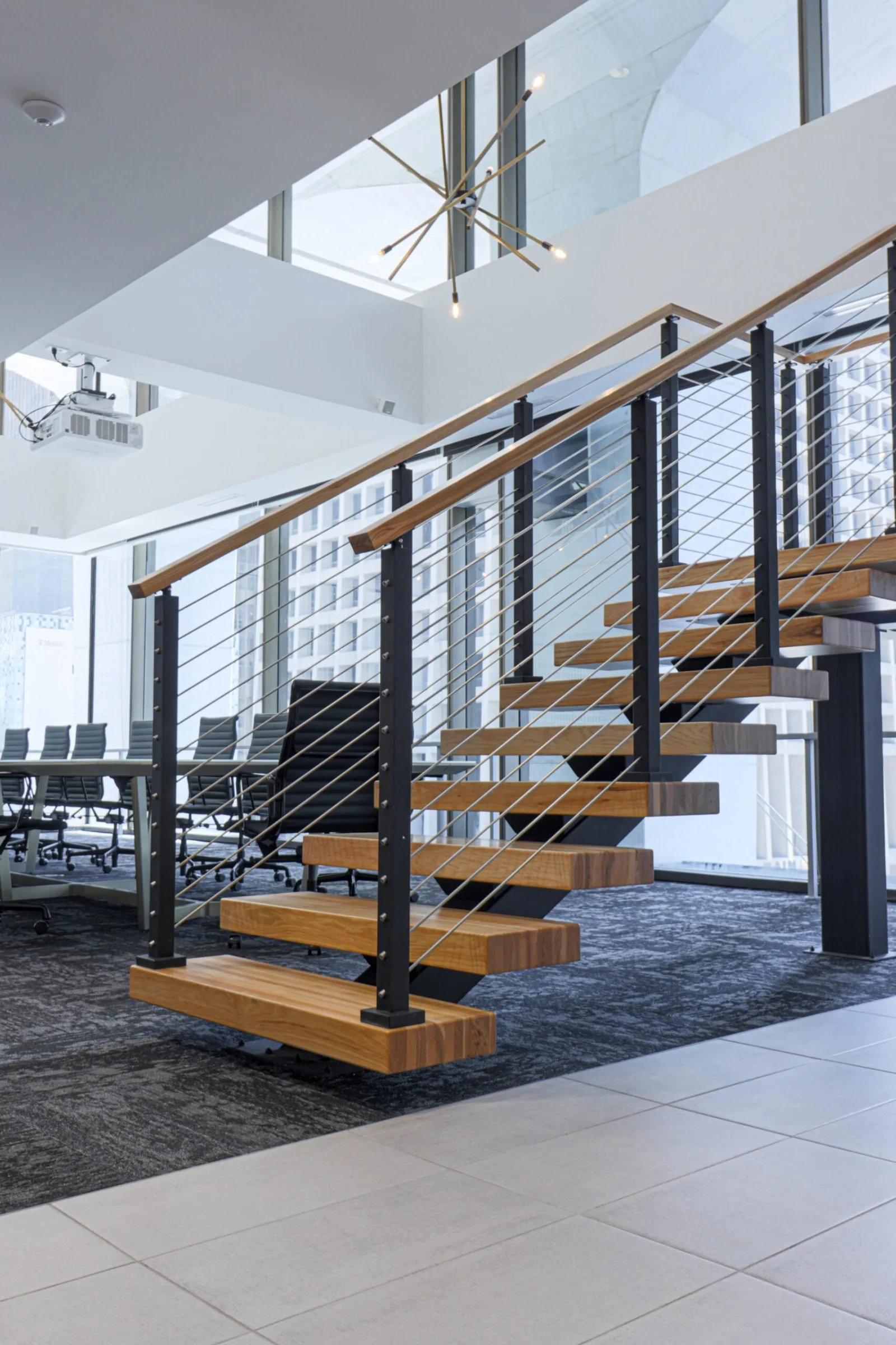 Floating stair seen from the lower floor against a glass curtain wall