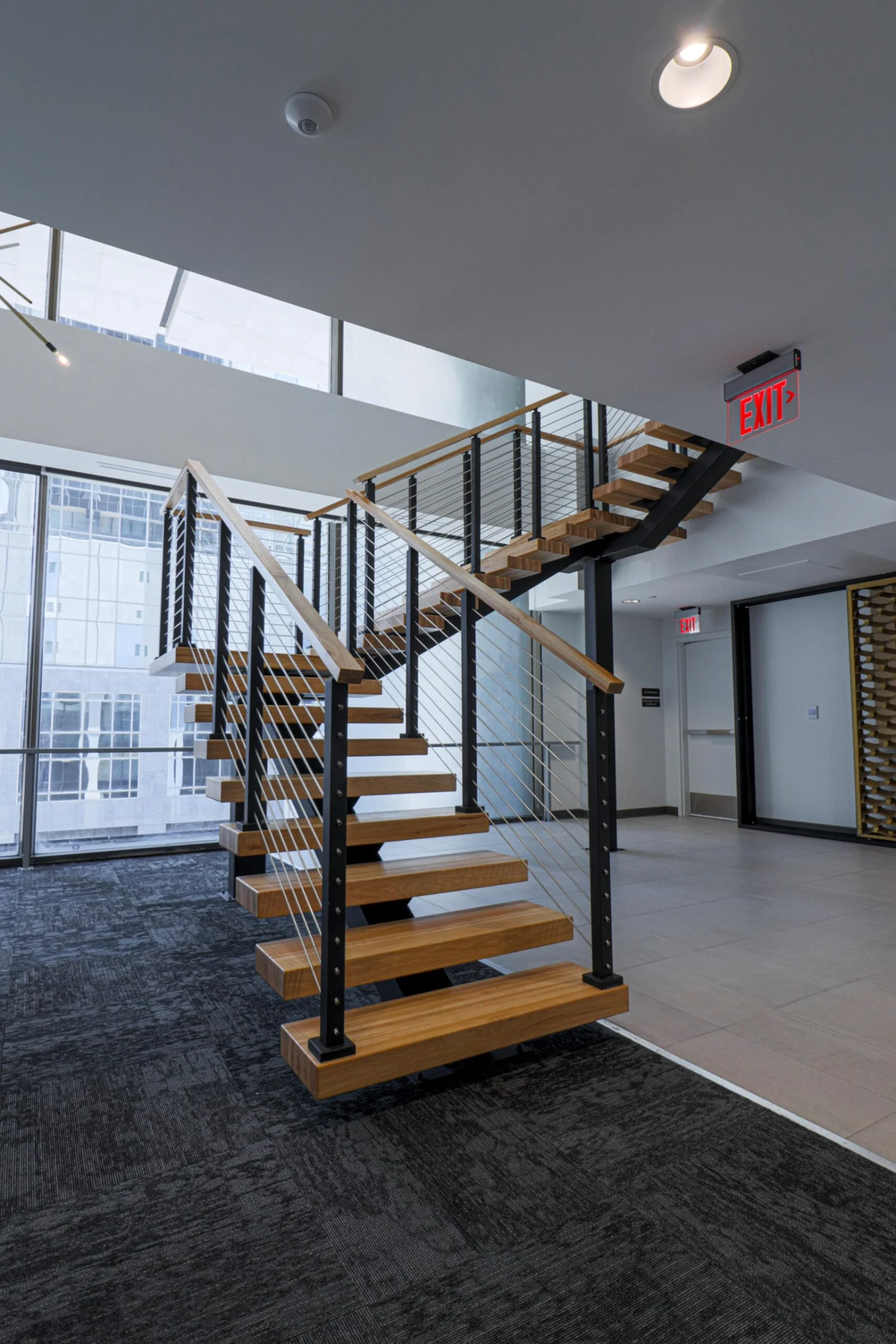 Angled view of the stair between carpet and tile with wine wall beyond
