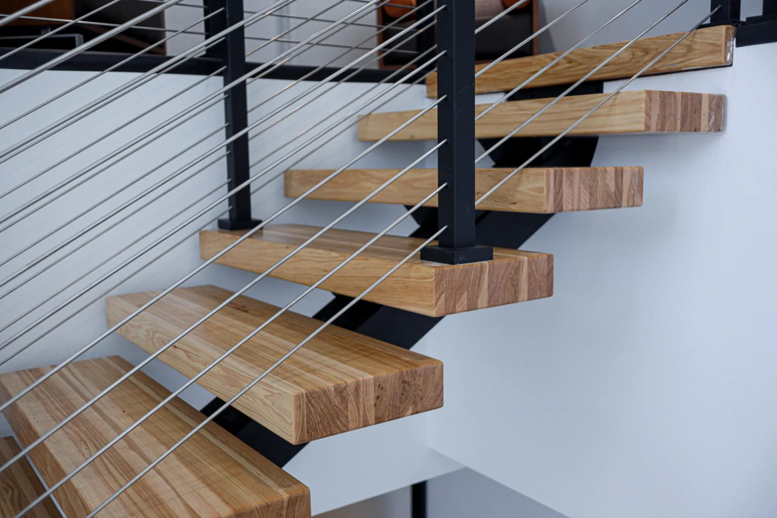 Close detail of cantilevered treads on a black center stringer with cable infill