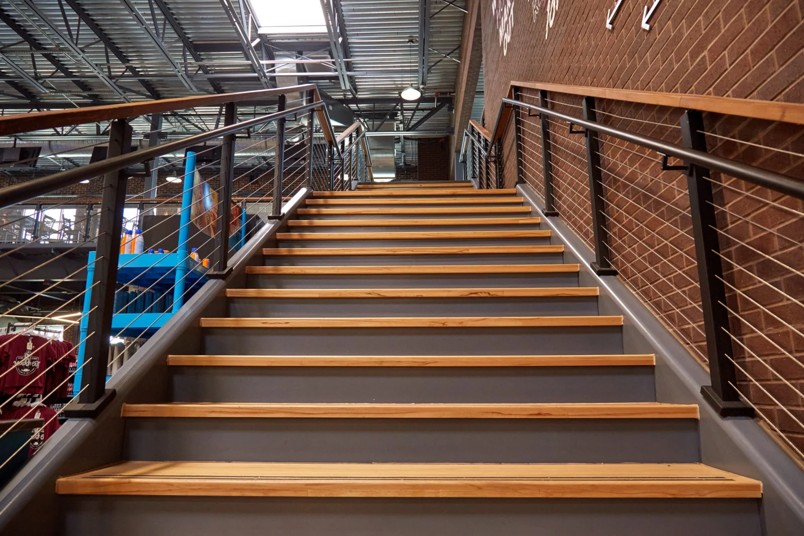 Looking up the staircase between two cable runs beside a brick wall