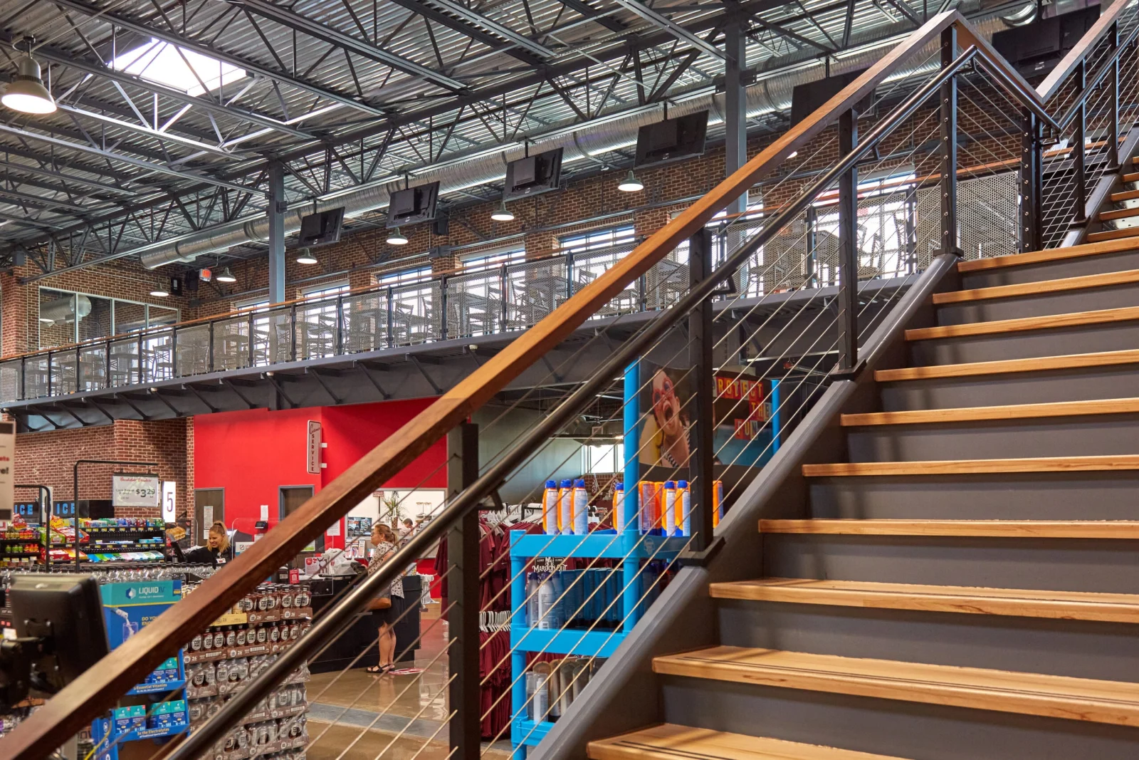 Store stair with wood treads and cable railing under an open steel ceiling