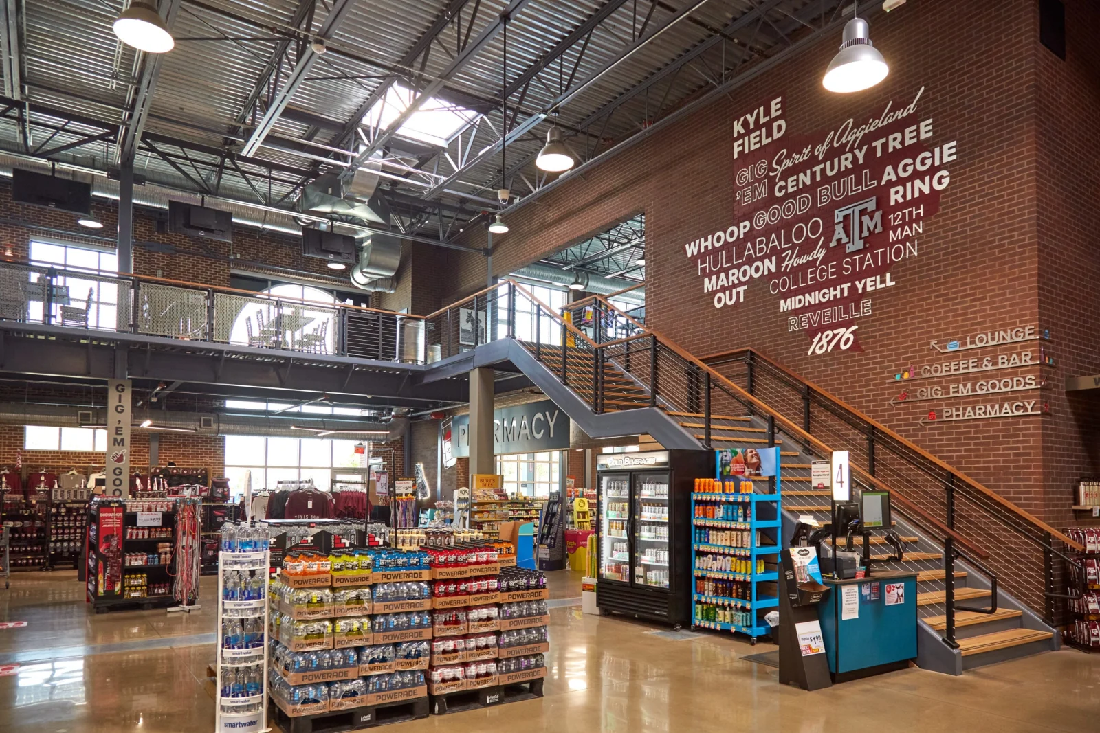 Black stair and mezzanine railing above packed grocery aisles in a brick-walled market