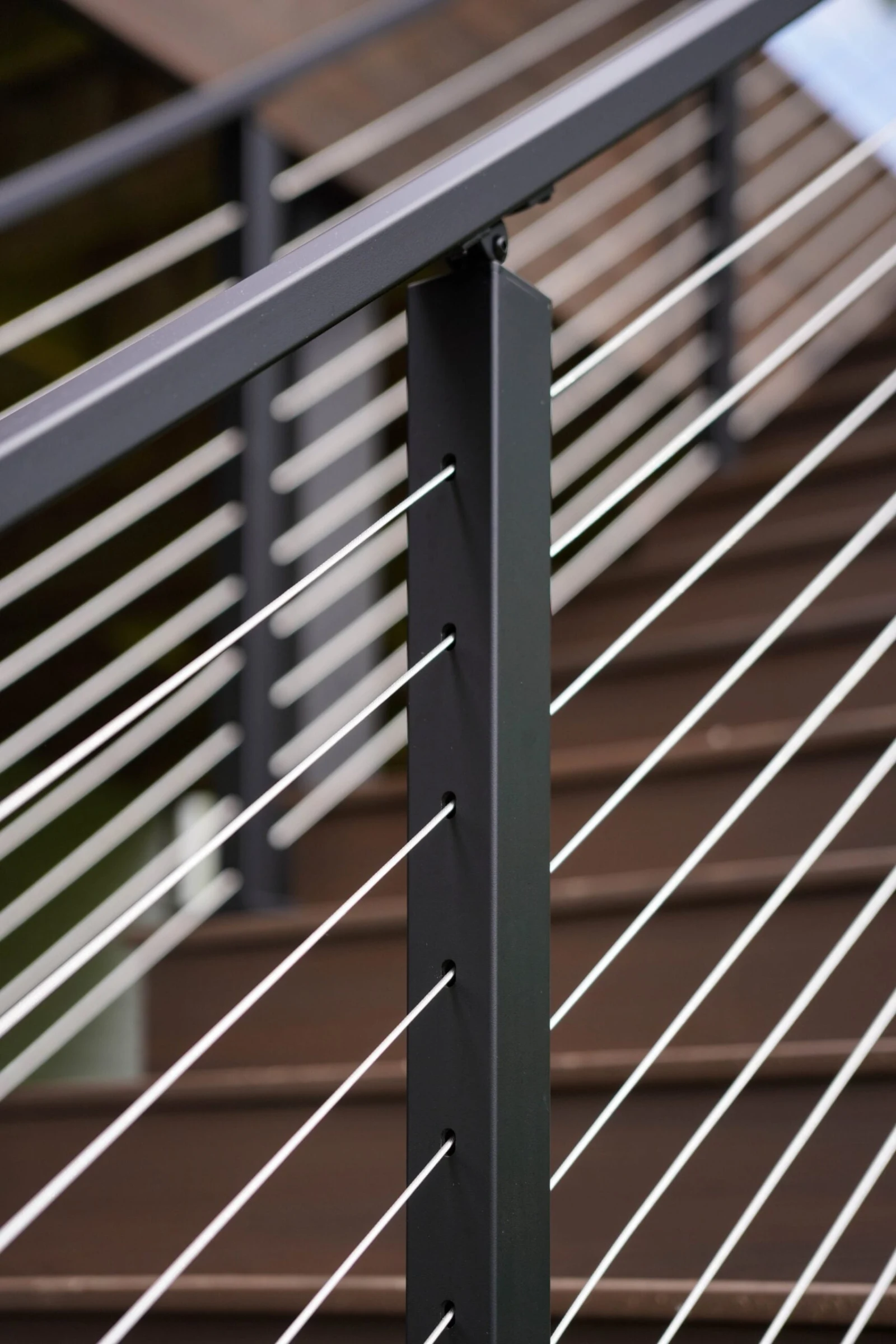 Single post catching light with cable lines running down over deck stairs