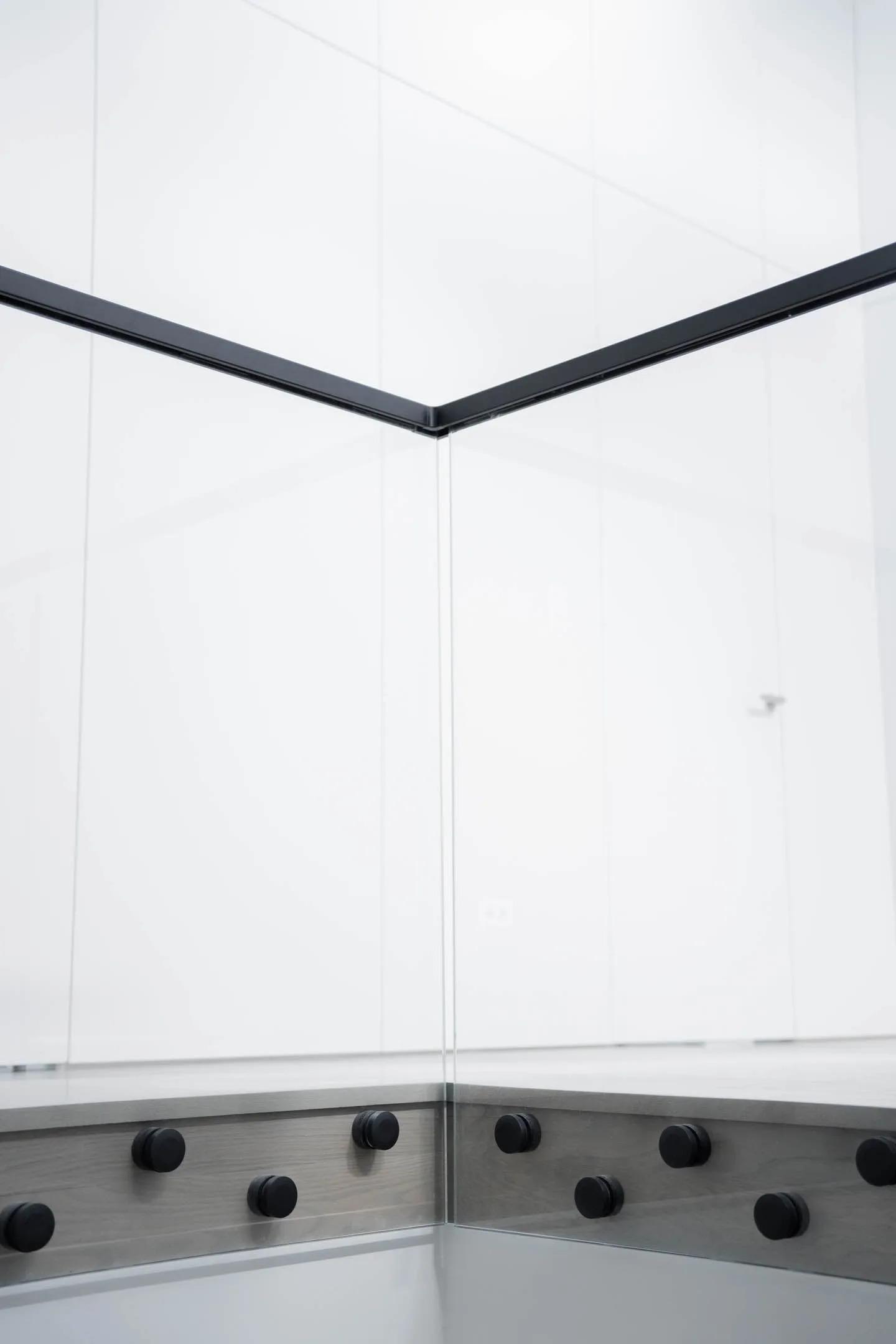 Glass panels meeting at an inside corner beneath a slim black cap rail
