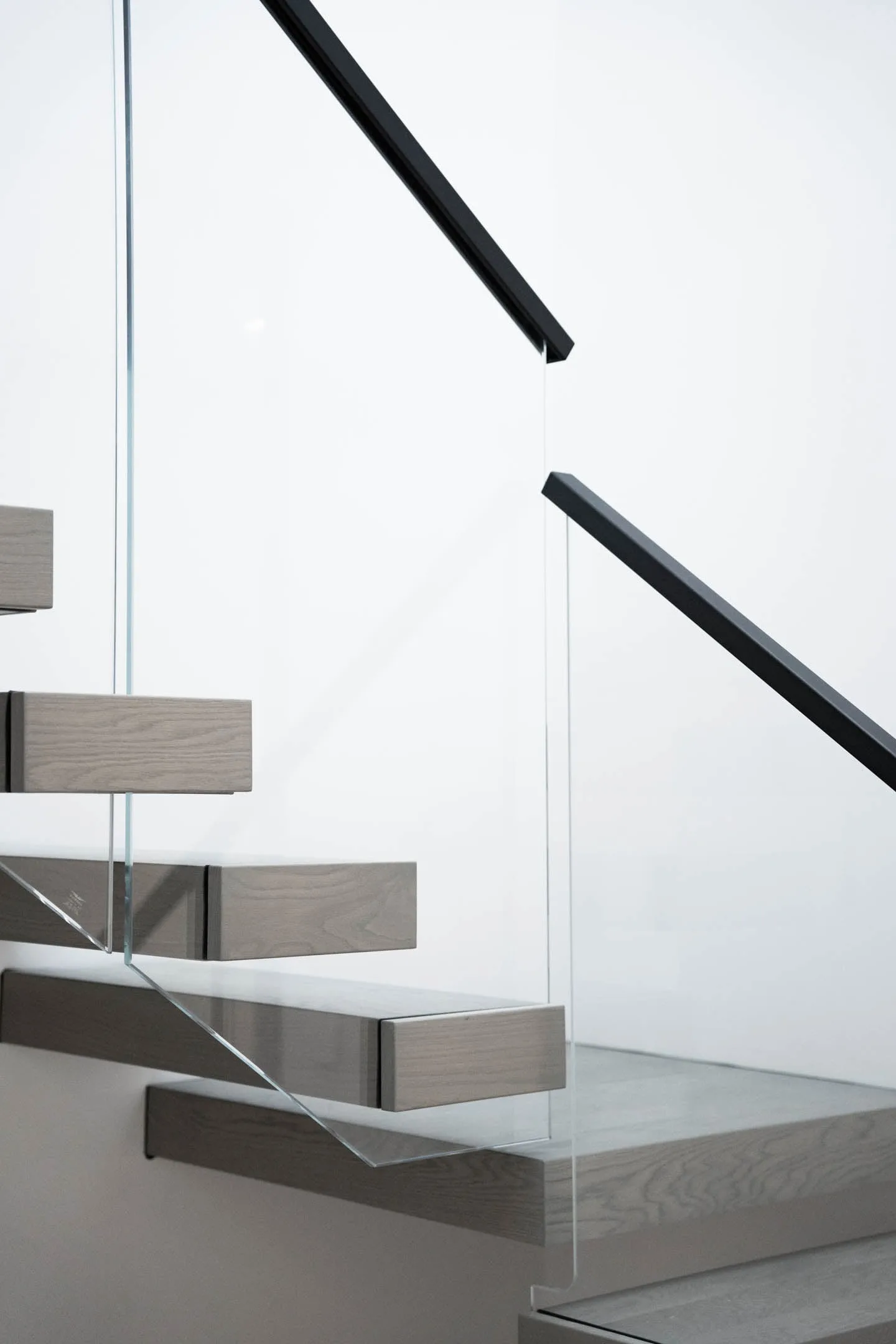 Side view of floating treads with glass infill and slim black handrails