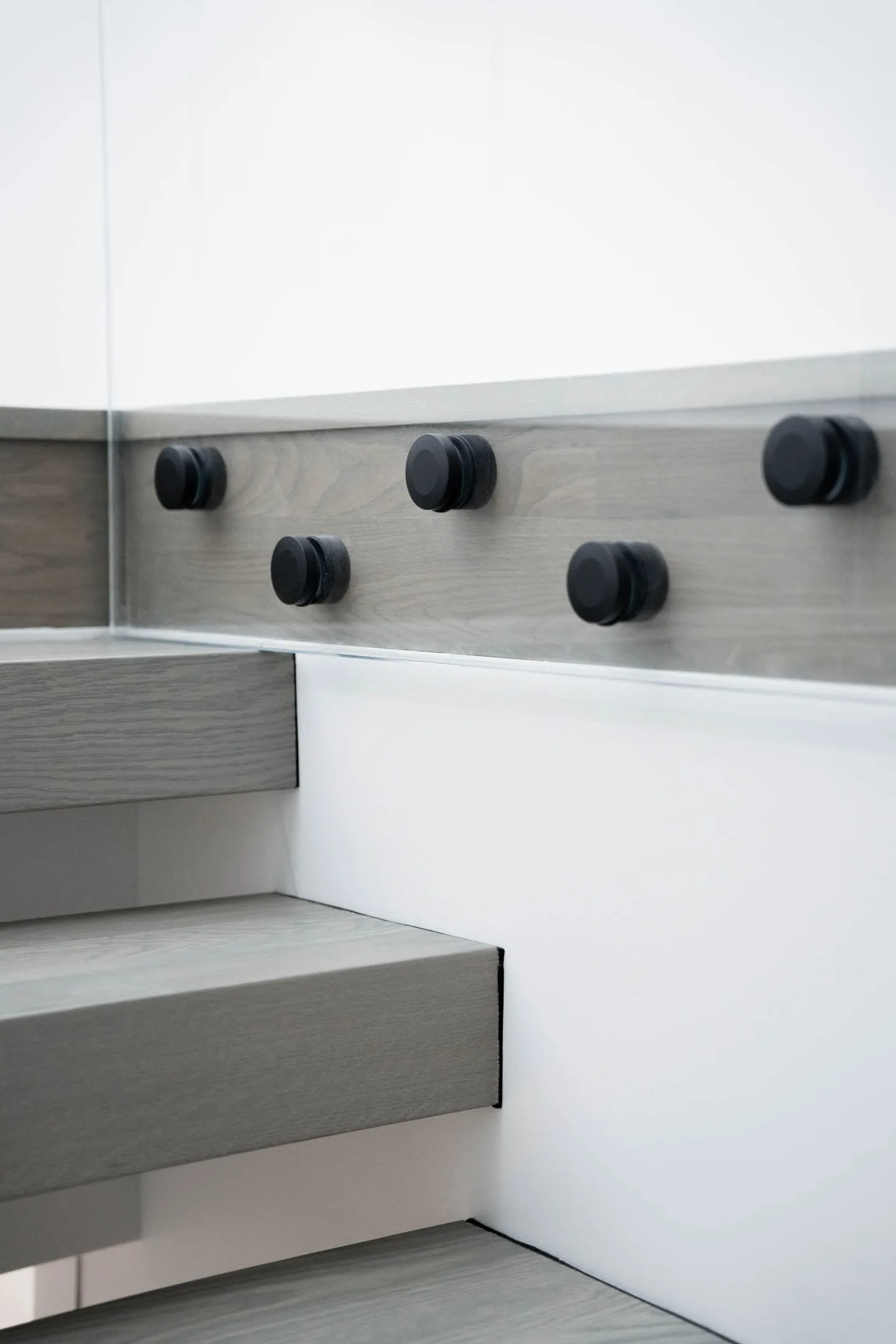 Round black hardware studs anchoring the treads along a gray wood fascia