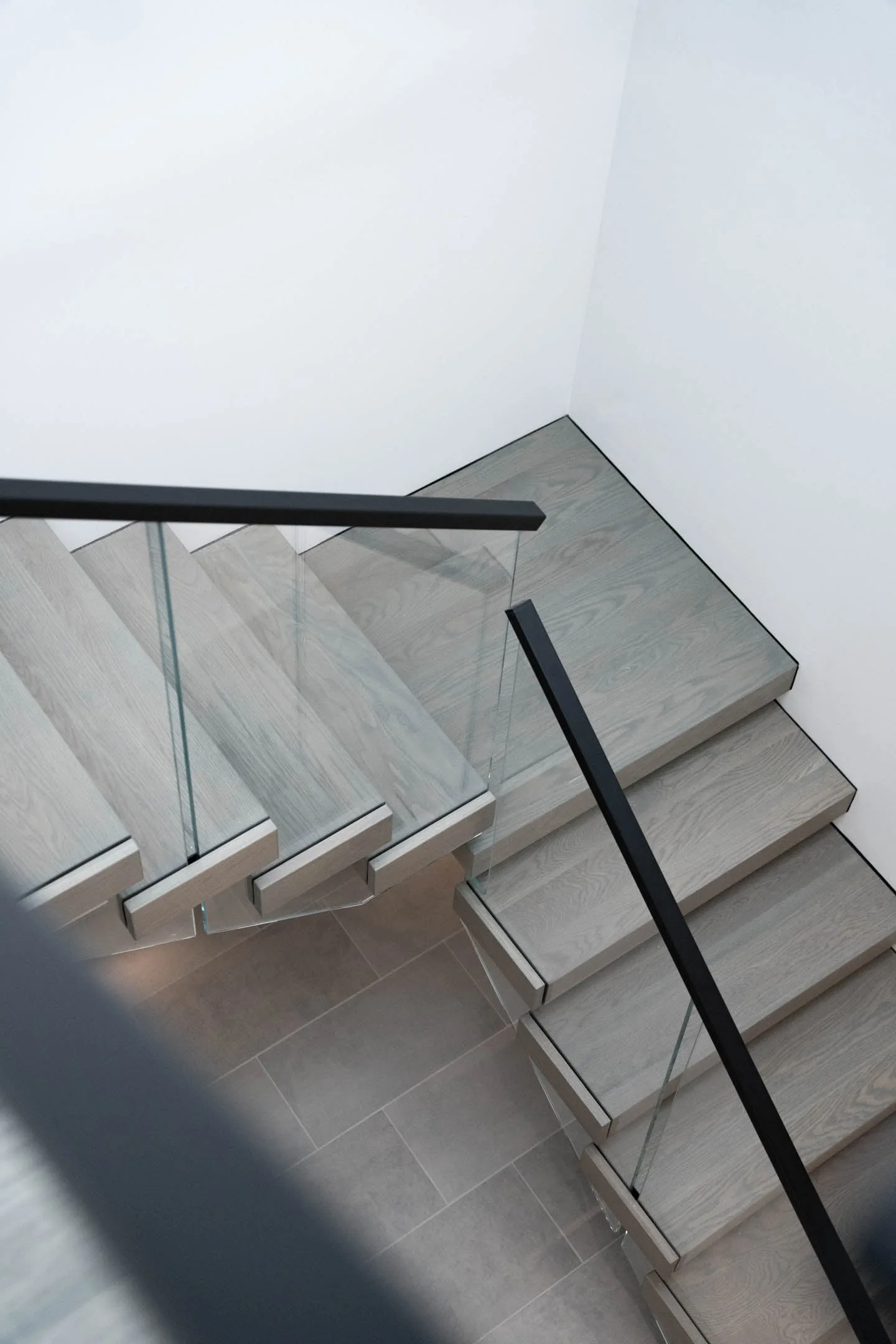 Overhead view of a landing turn with glass railing above a tiled floor