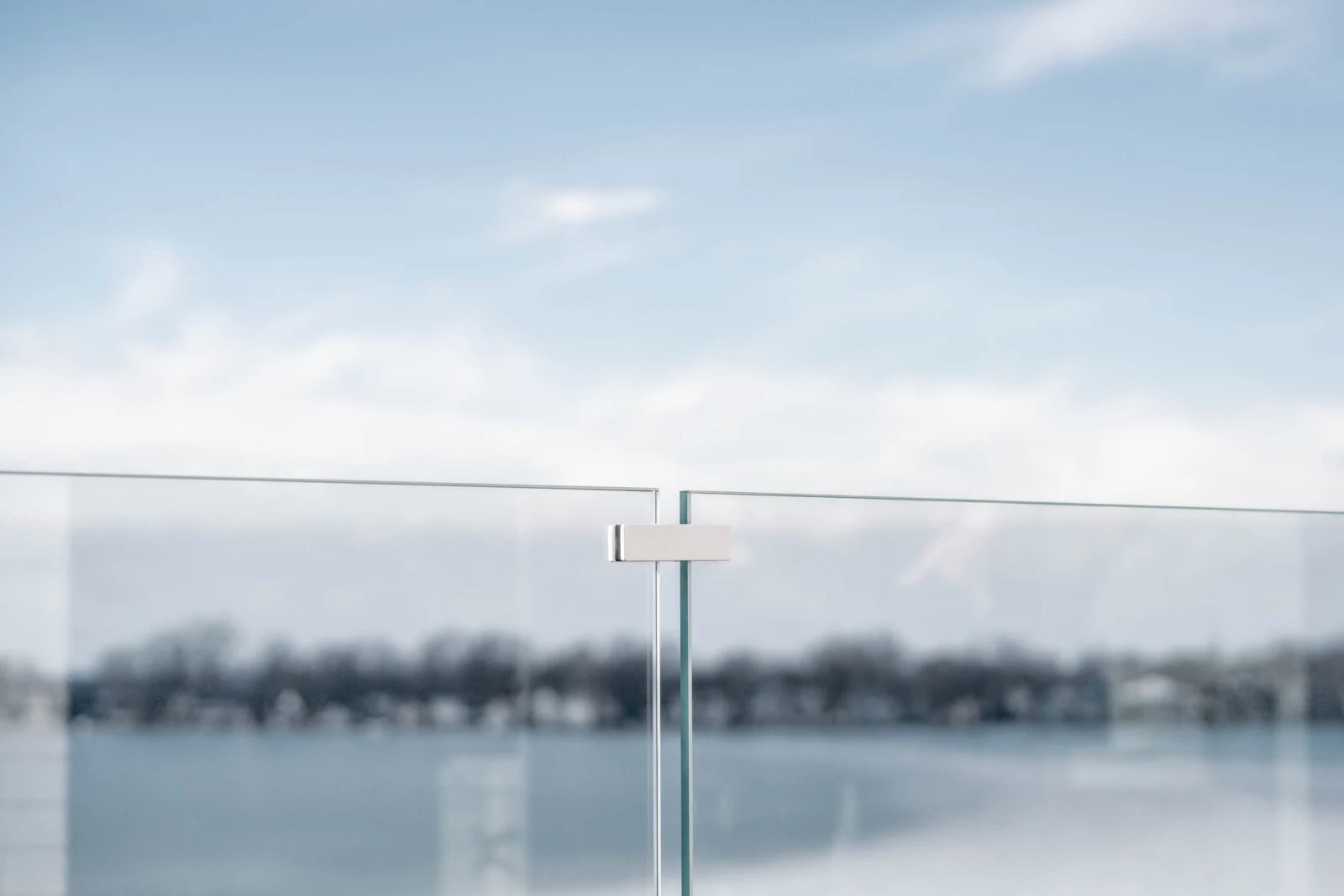 White stabilizer clip joining two glass panels at their top edge