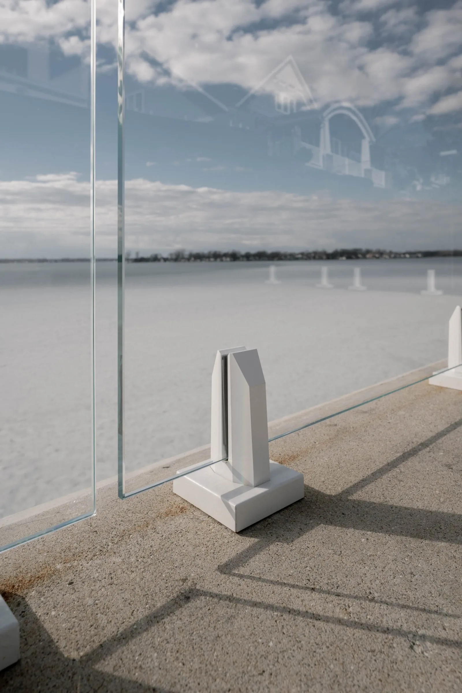 Close view of a white base clamp gripping a clear glass panel