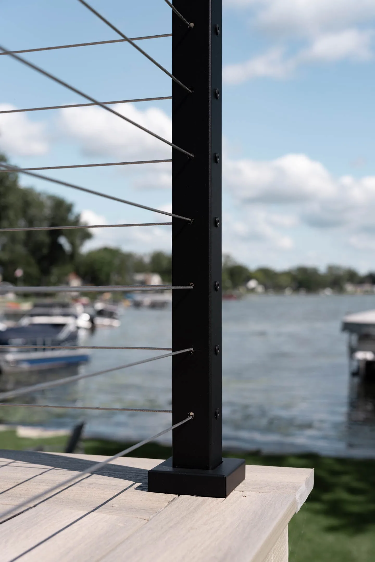 Post base anchored to gray decking with moored boats across the water