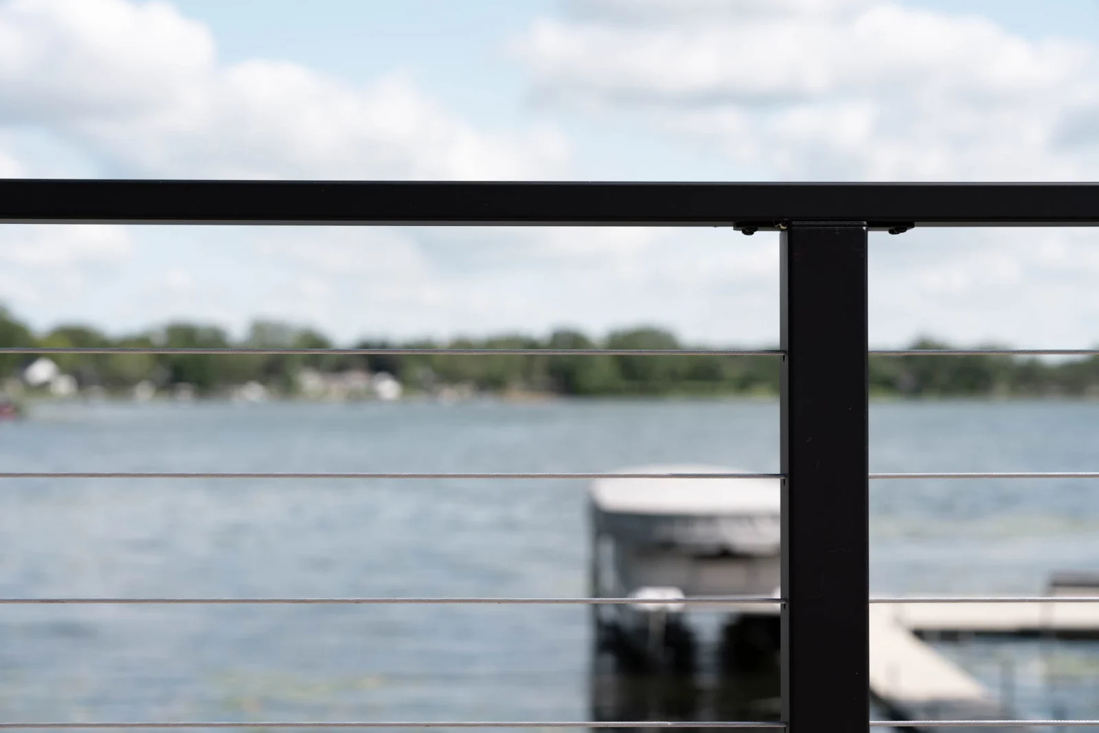 Lake and boat dock framed between the top rail and cable lines