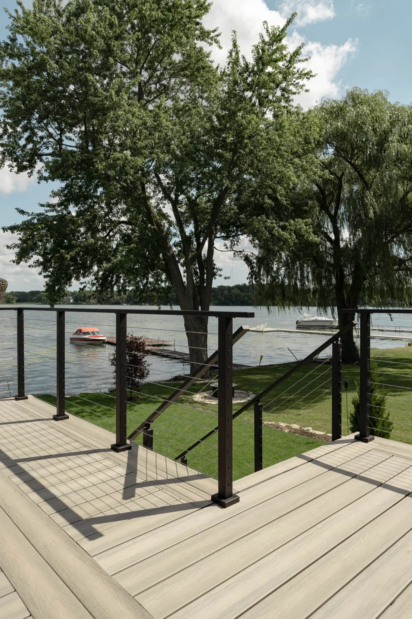 Deck corner where the railing turns toward a stair opening and lake