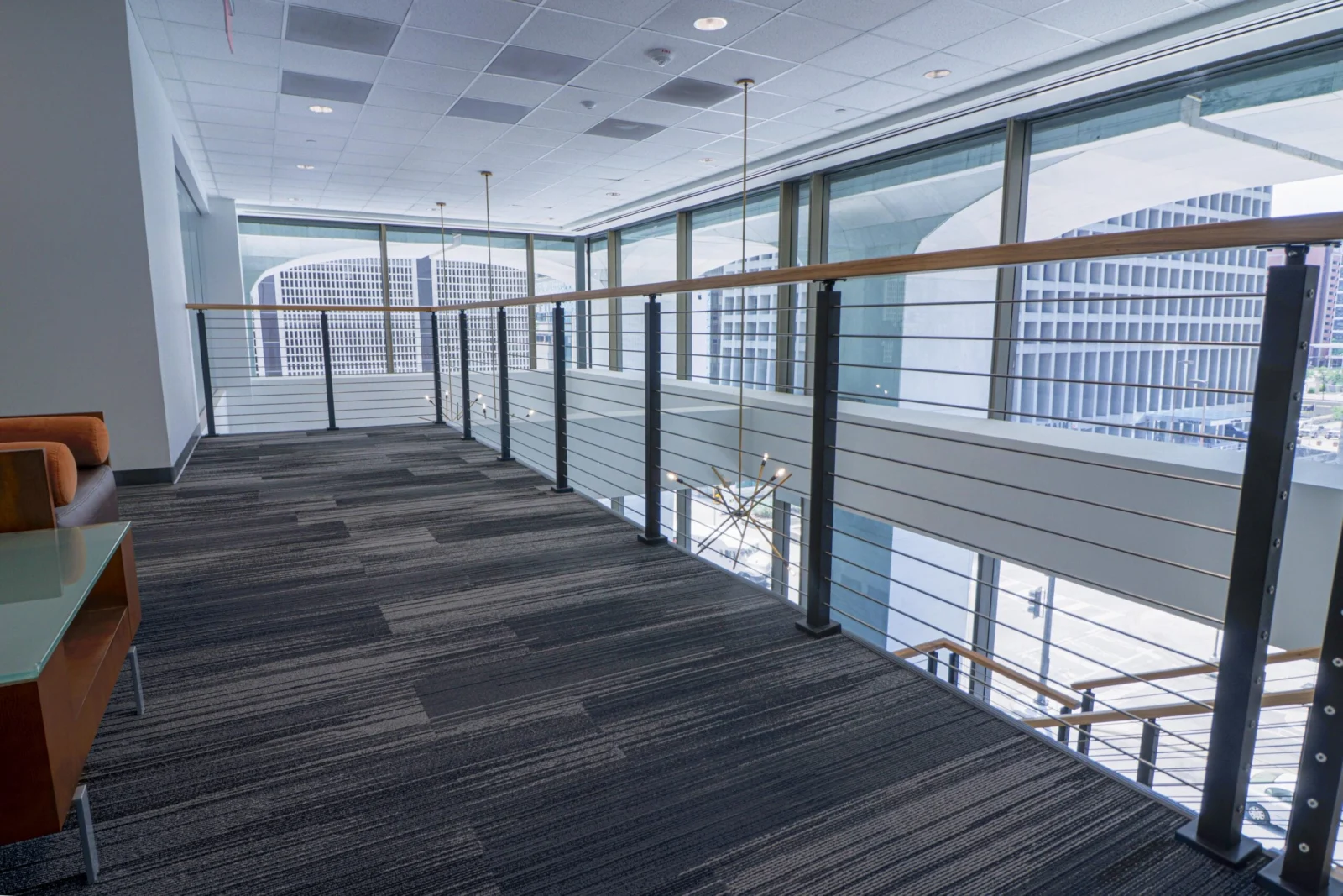 Office mezzanine walkway edged with cable railing and a wood top rail
