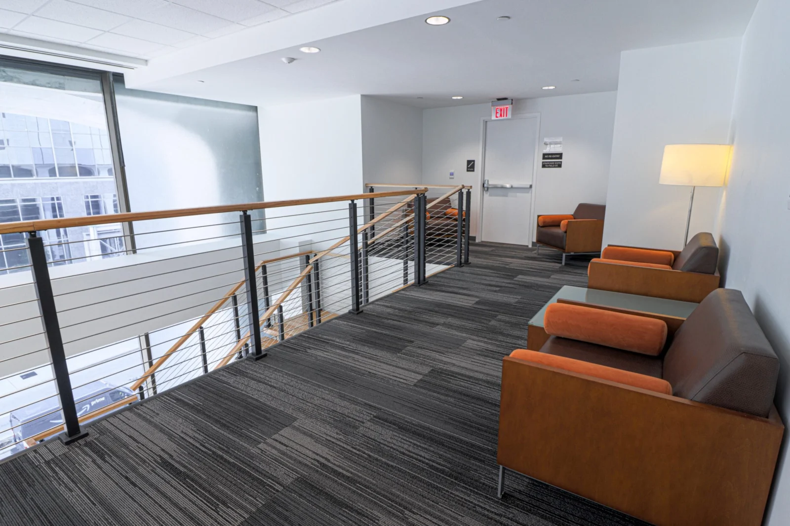 Railing along a lounge area with leather armchairs and a window wall