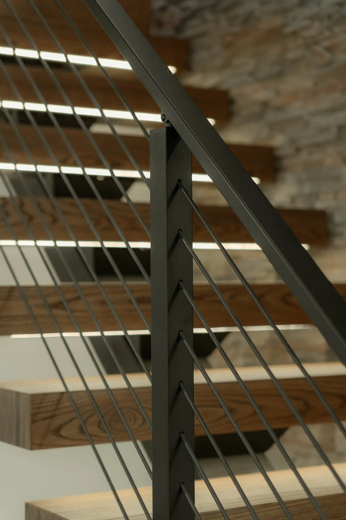 Looking up through vertical rods at the underside of open wood treads