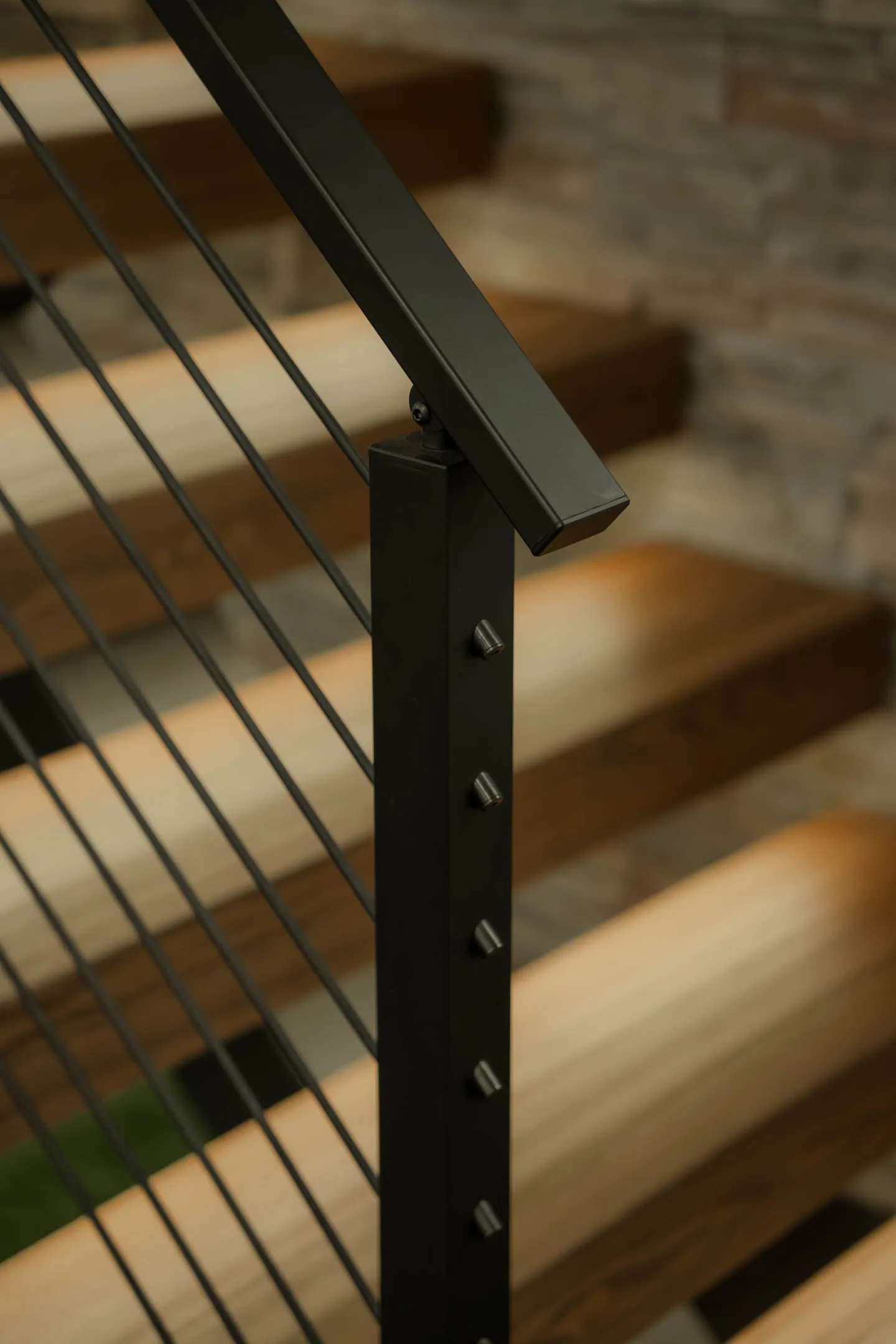 Black post with exposed rod fittings meeting the angled top rail