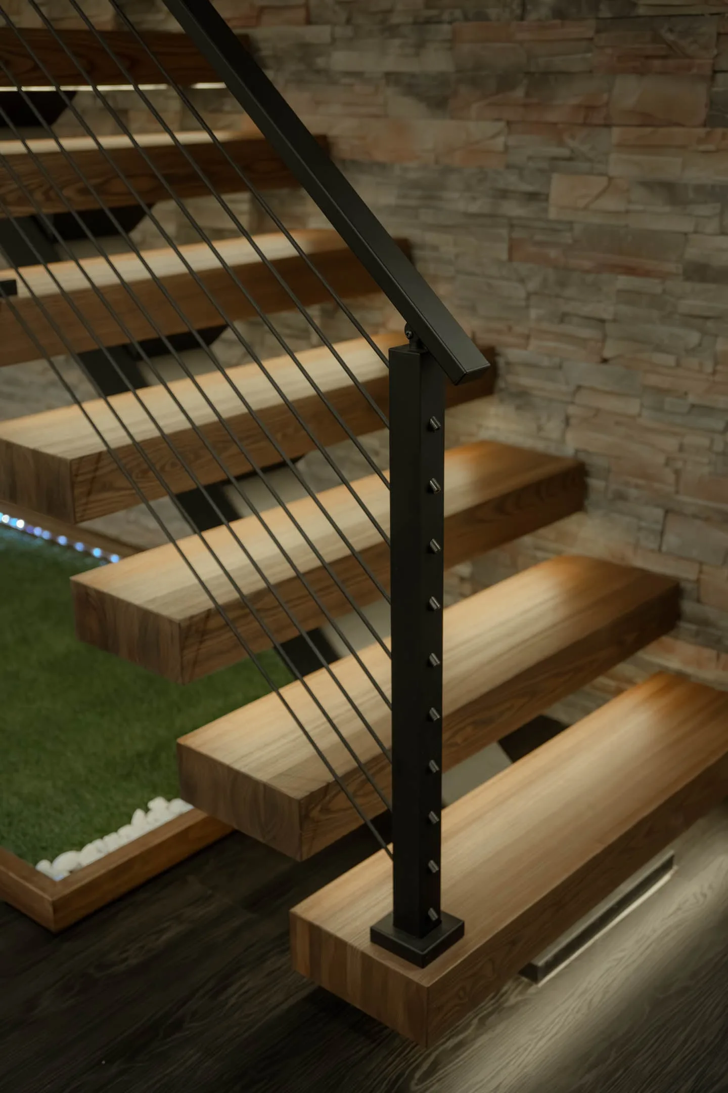 Lit treads step down past the stone wall with rod railing running alongside