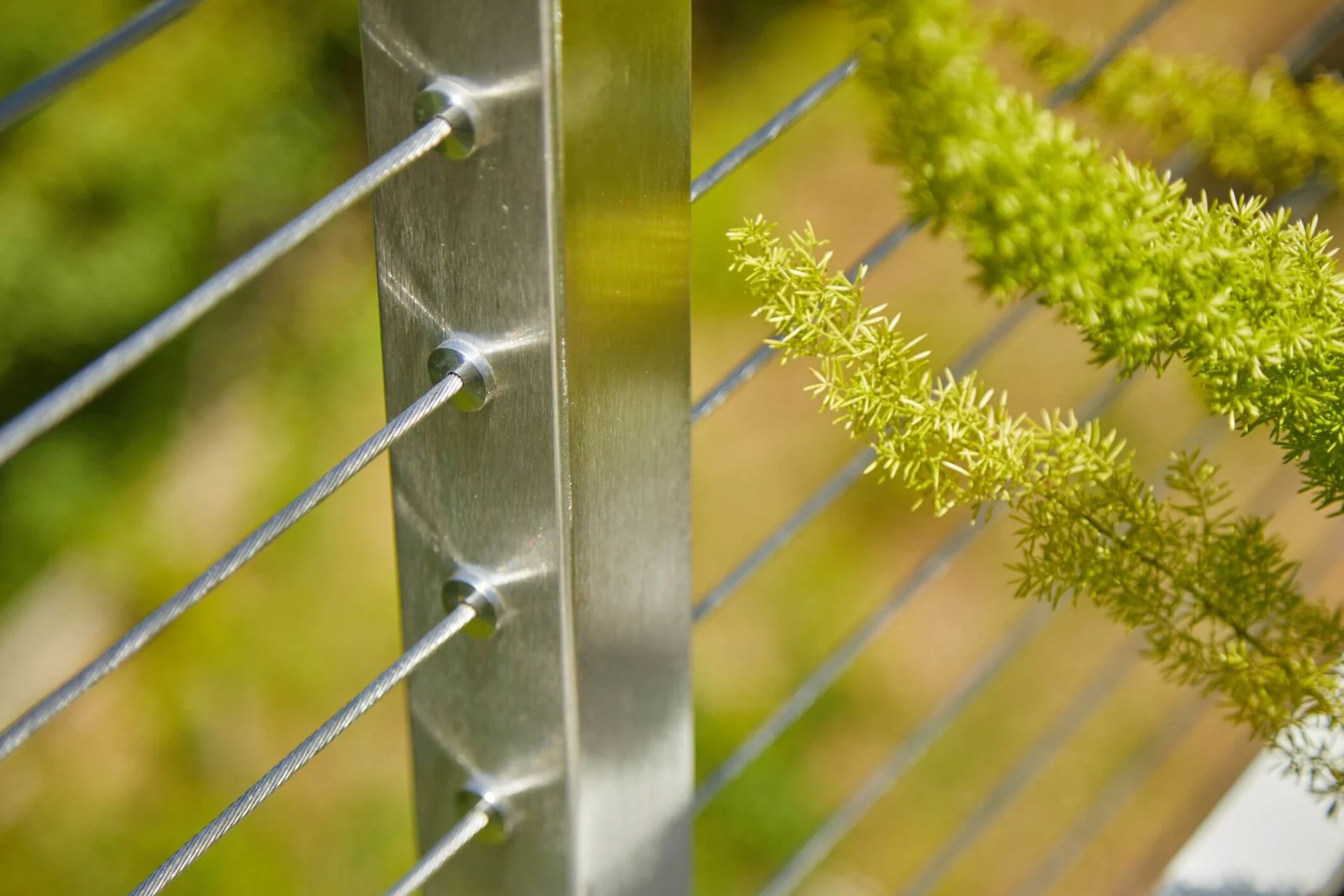 Close view of a brushed stainless post with cables threaded through drilled holes