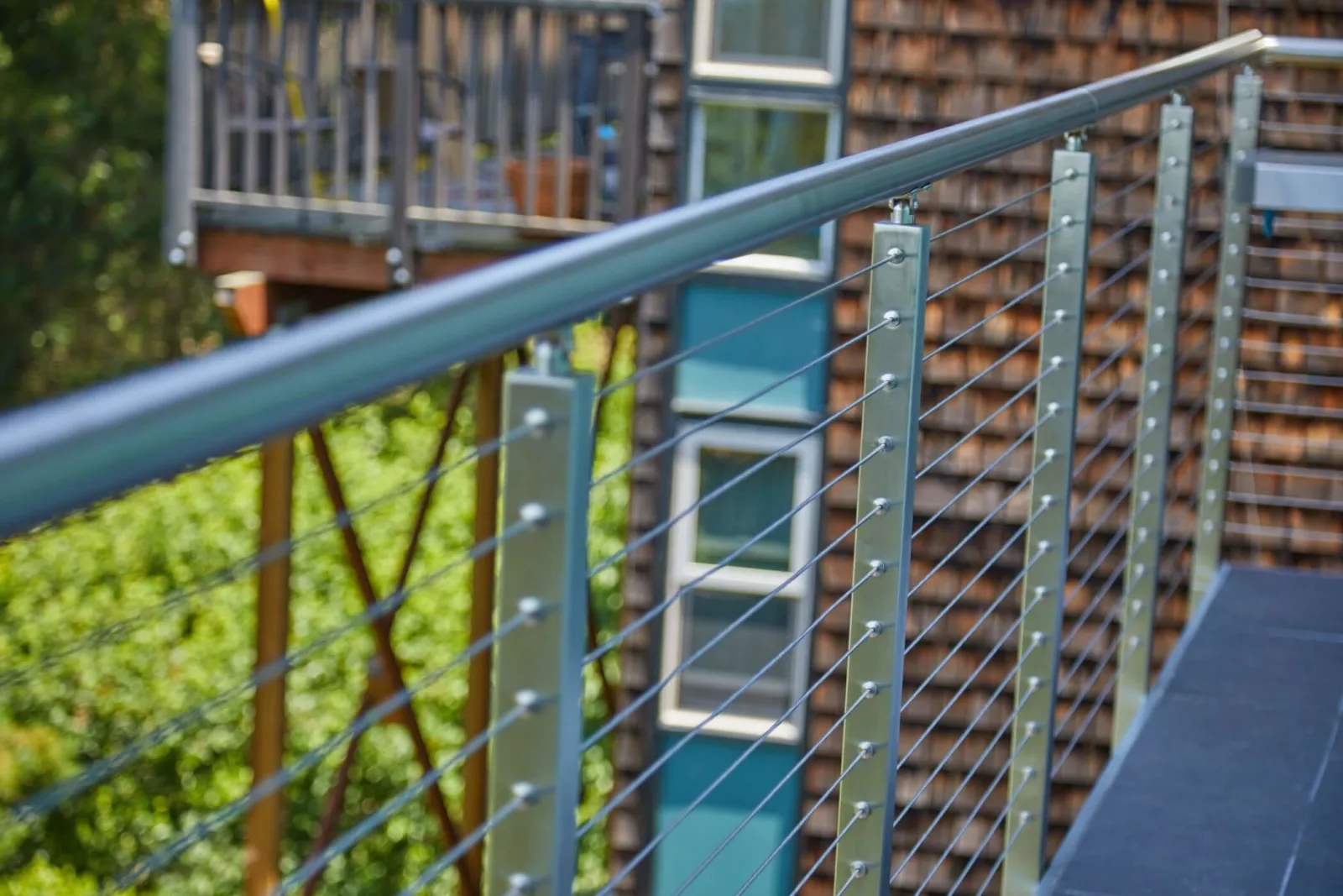 Angled view along the top rail past posts toward a shingled wall