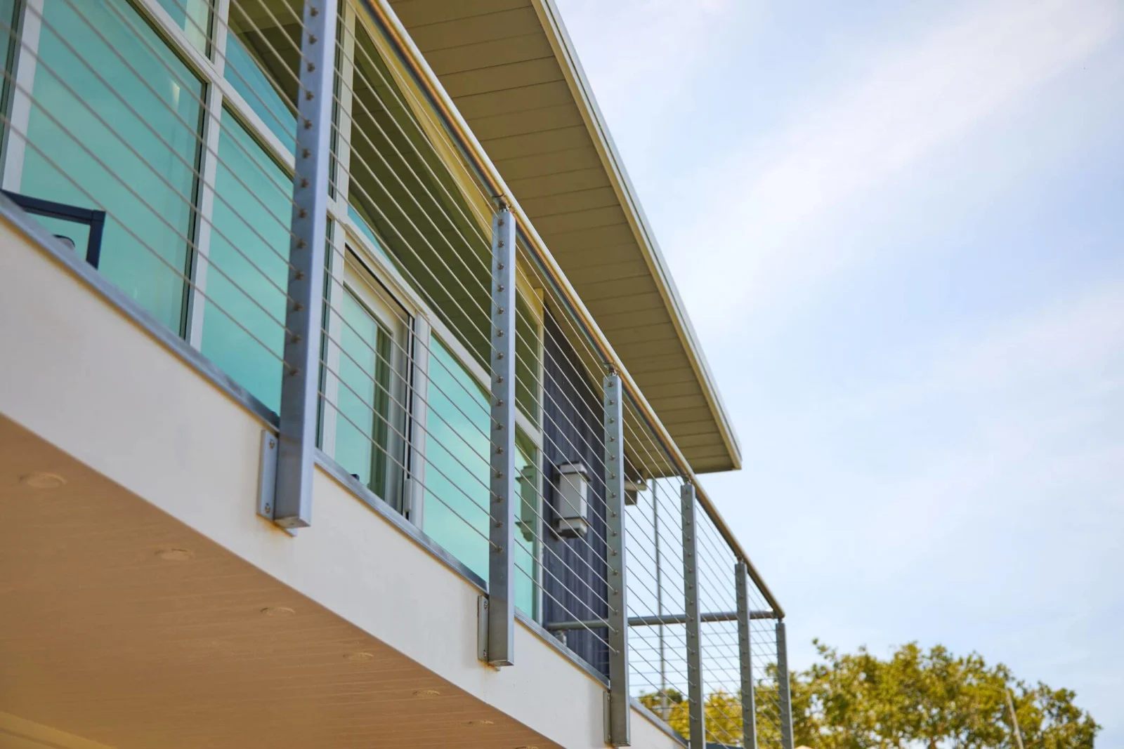 Looking up at side-mounted stainless posts carrying cable railing along an upper balcony
