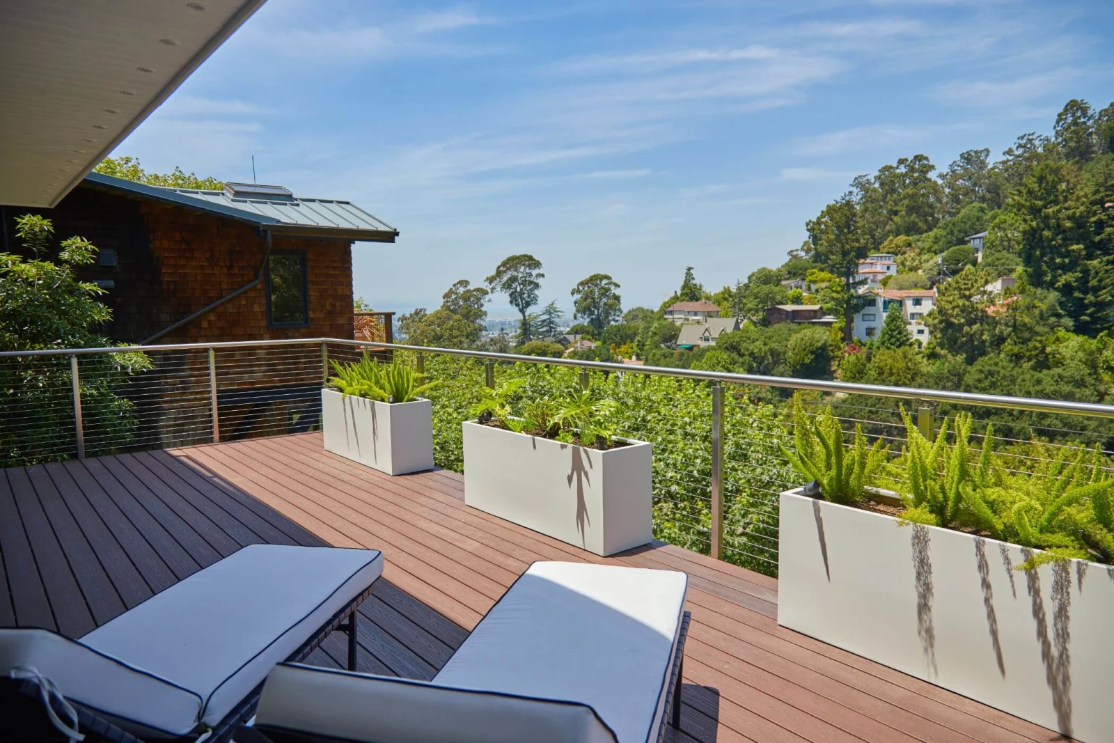 Wide deck view with loungers, planters, and cable railing framing the valley