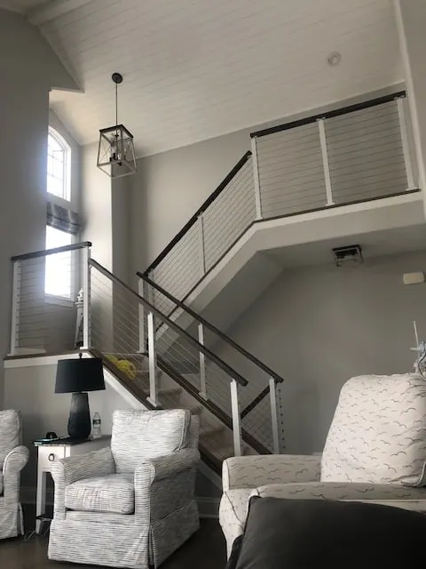 Living room seating beside a stair with white posts and dark top rail