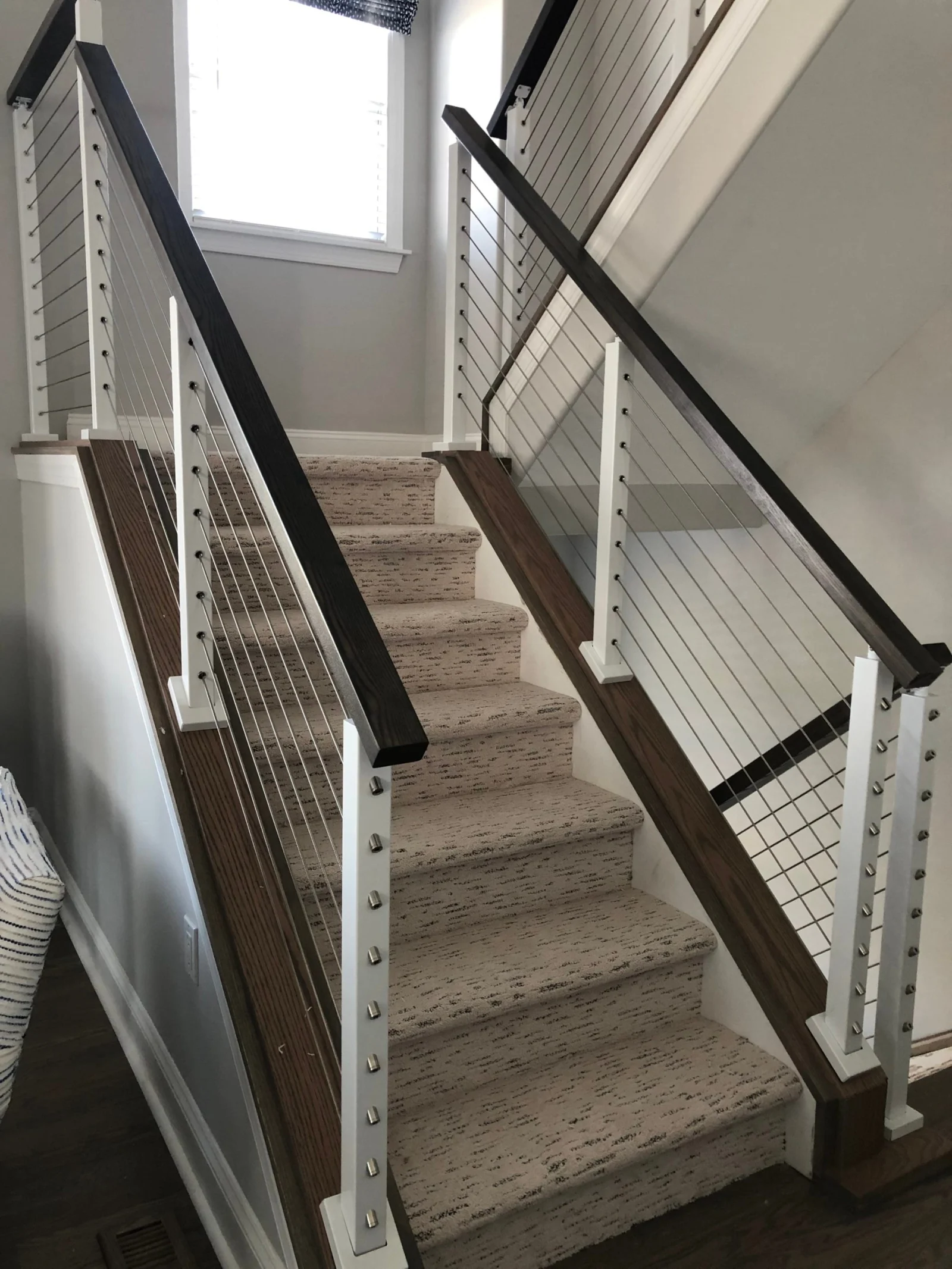 Straight run of carpeted stairs flanked by white posts and dark handrails