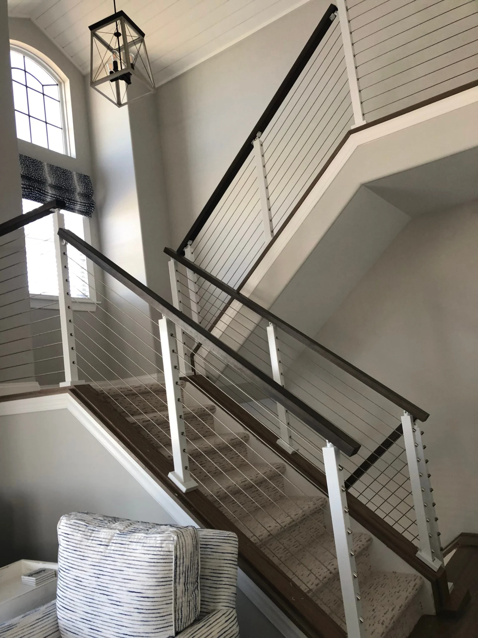 Stairwell with arched window and two runs of white-post cable railing