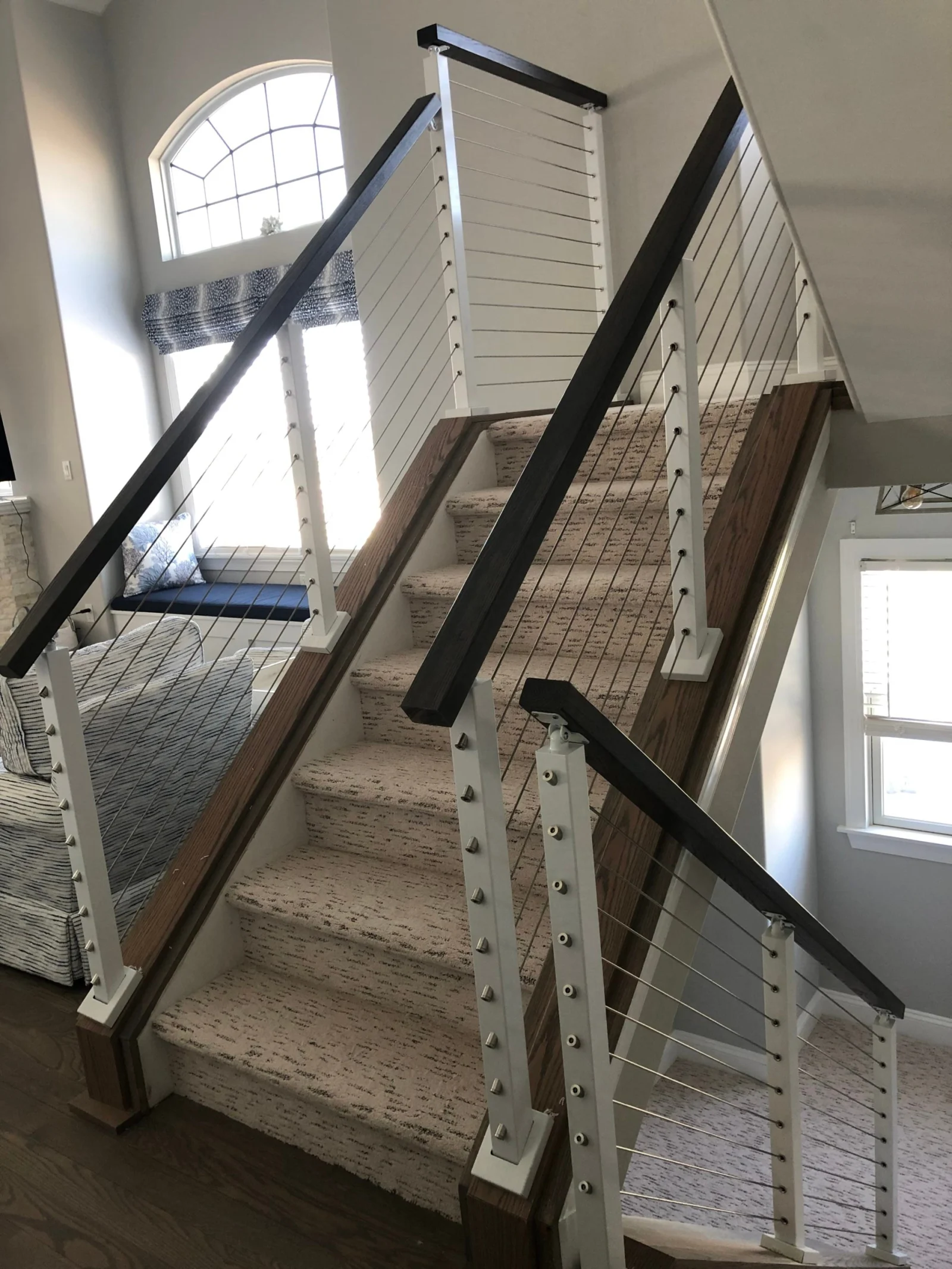 Stair and landing railings meeting below an arched window in the entry