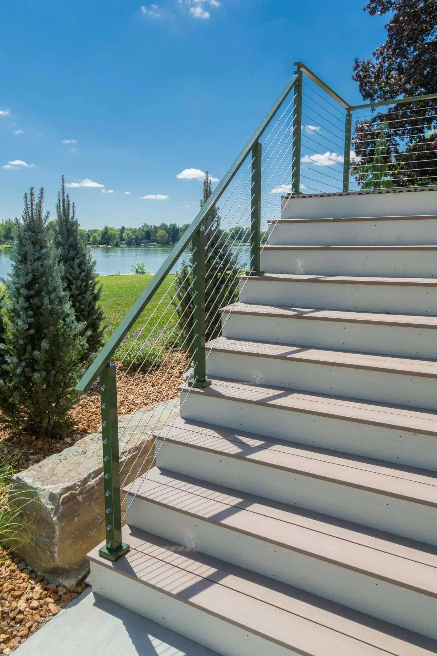 Composite steps rising beside a green powder-coated post and cable railing