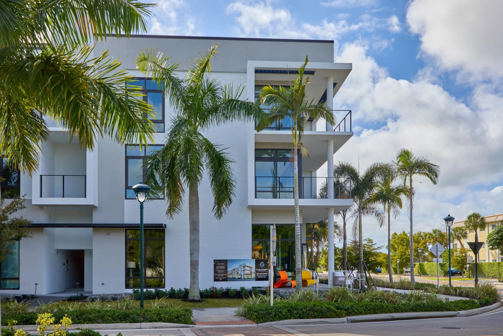 Corner view of the white condo building with railed balconies and palm landscaping