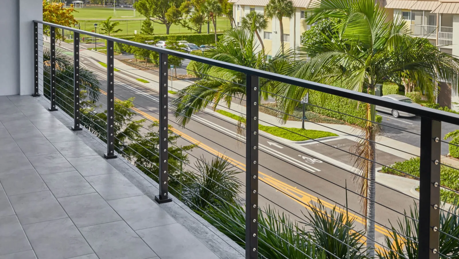 Balcony cable railing overlooking a palm-lined street from the second level