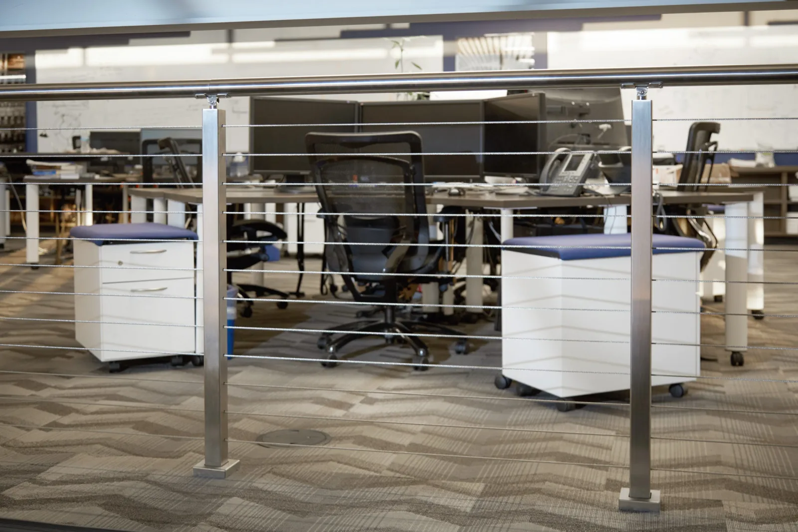 Stainless posts and cable infill separating workstations inside a research facility
