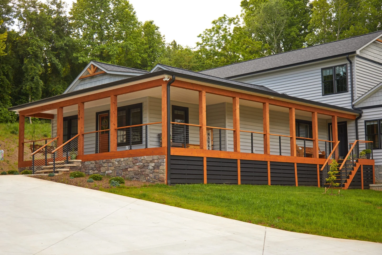 Ranch home with a wrap-around porch, timber posts and cable railing along the front