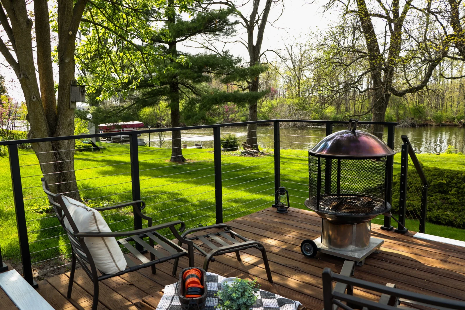 Wide view of the deck corner wrapped in black cable railing above the lawn