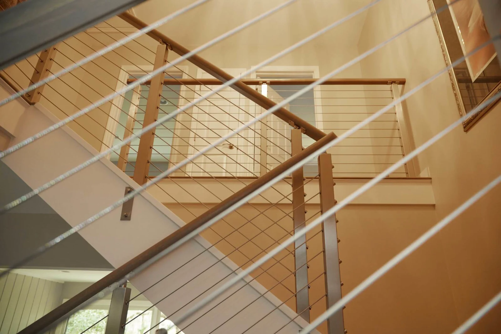 View up the stairwell through taut cables to the railing on the upper level